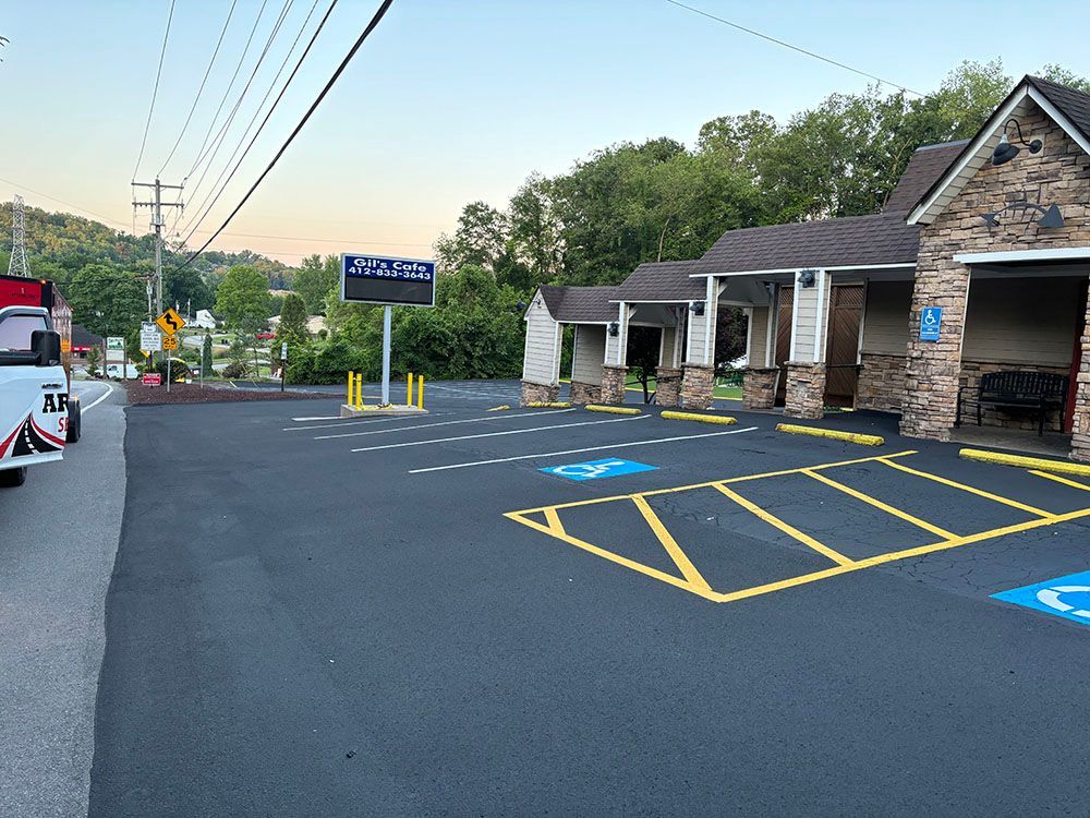 Paved parking lot with handicap spaces in front of a stone and wood building, utility poles in background.