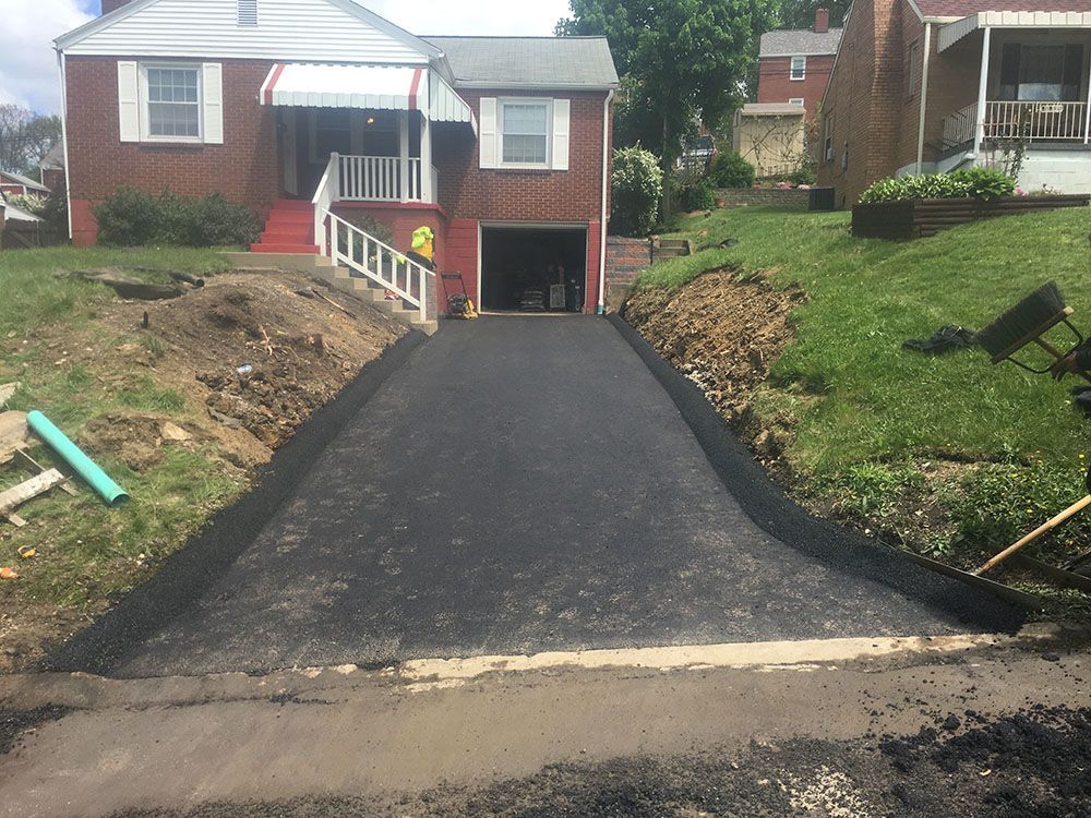 Asphalt driveway leading up to a brick house with a garage.