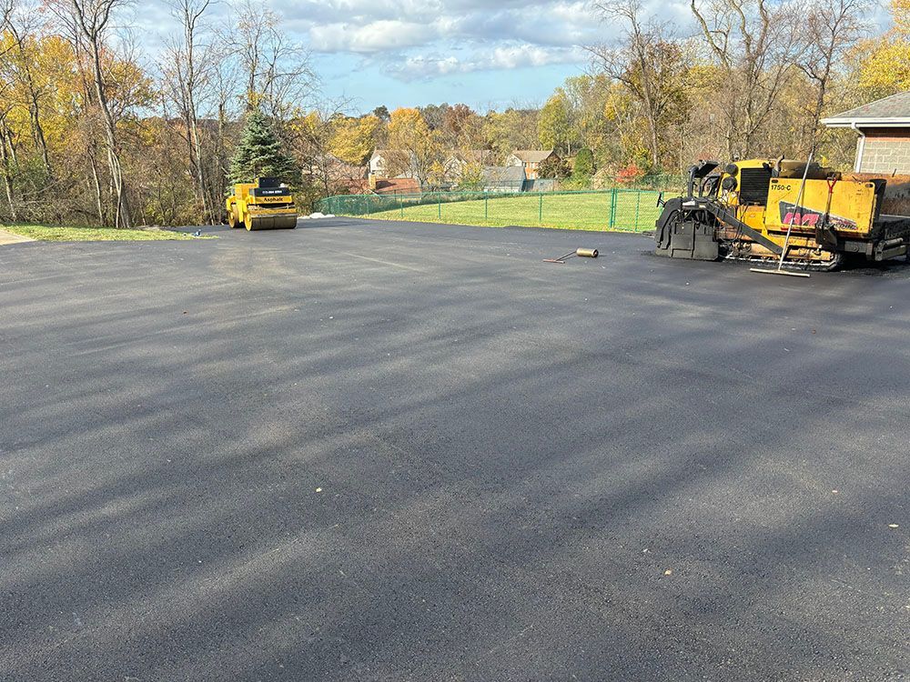 Newly paved asphalt parking lot with construction equipment.