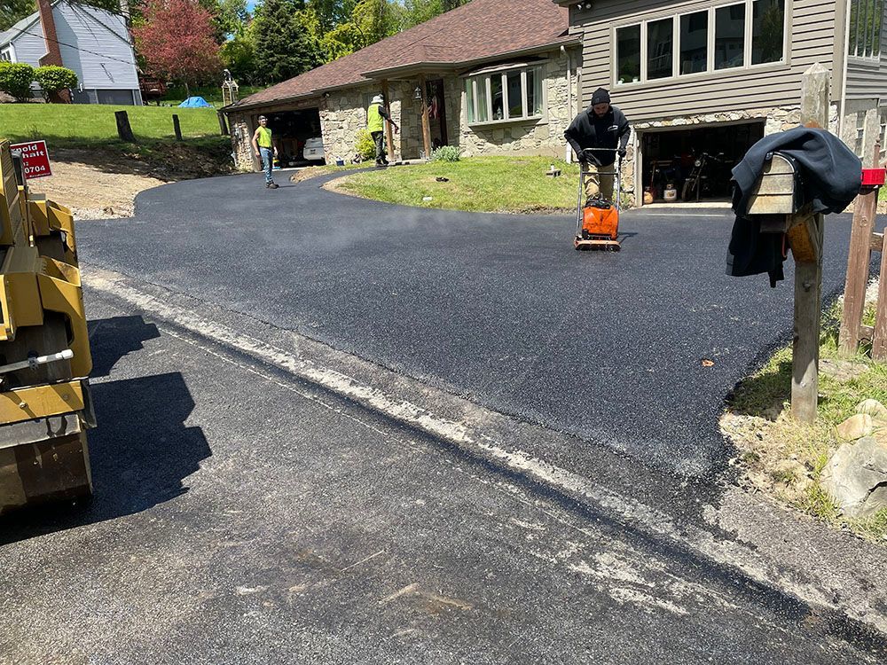 Driveway paving in progress; workers operating machinery.