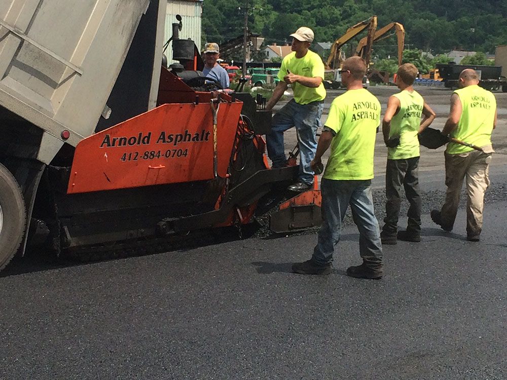 Asphalt paving crew at work, a dump truck pouring asphalt into a paving machine.
