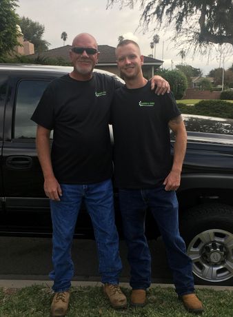 Two men are posing for a picture in front of a truck.