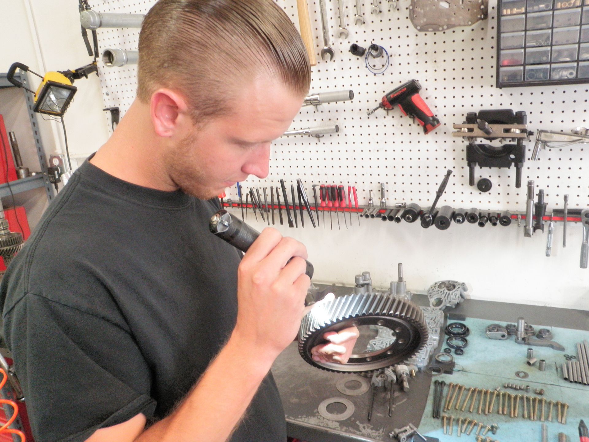 A man is checking a transmission using a flashlight