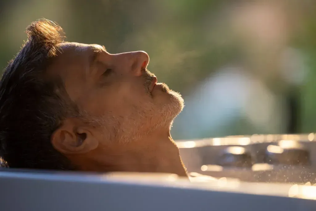 A man is laying in a hot tub with his eyes closed.