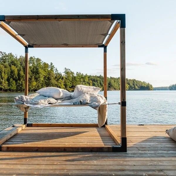 A canopy bed on a dock overlooking a lake