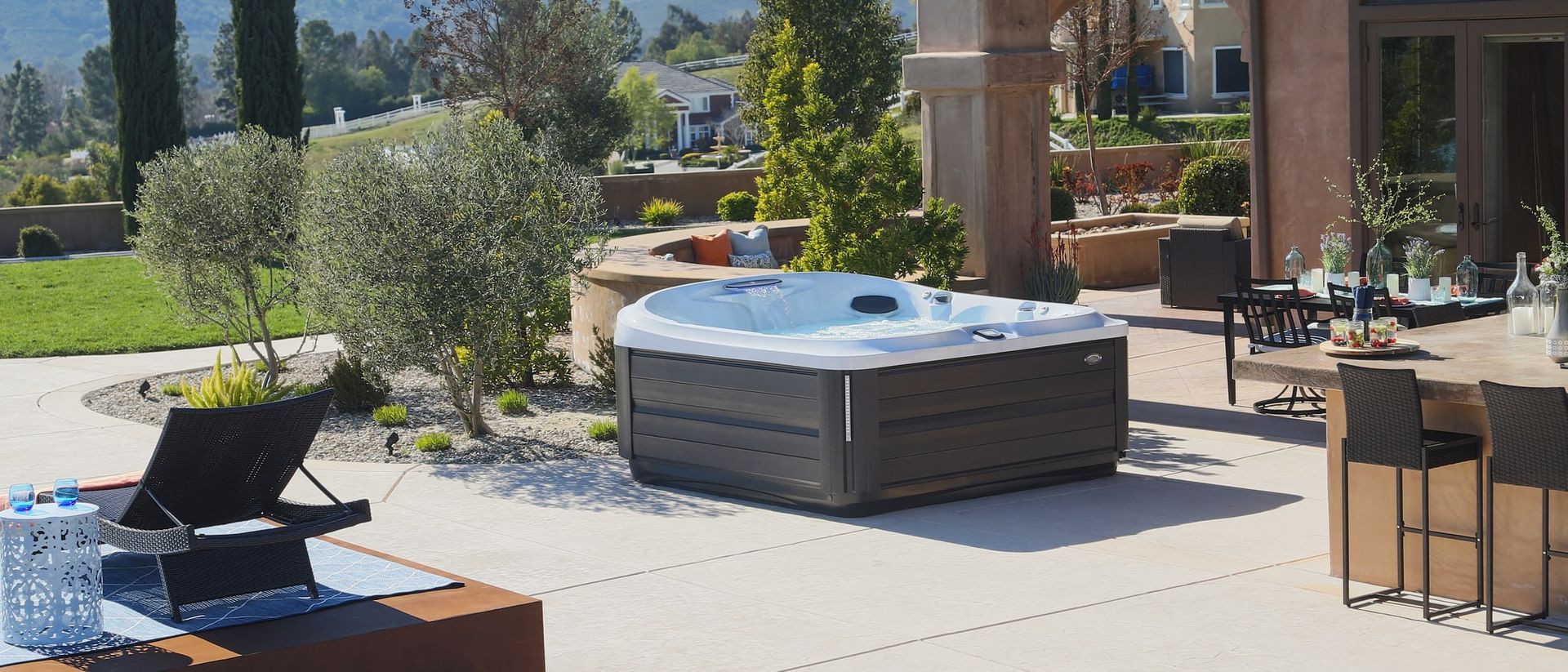 A hot tub is sitting on a patio next to a table and chairs.