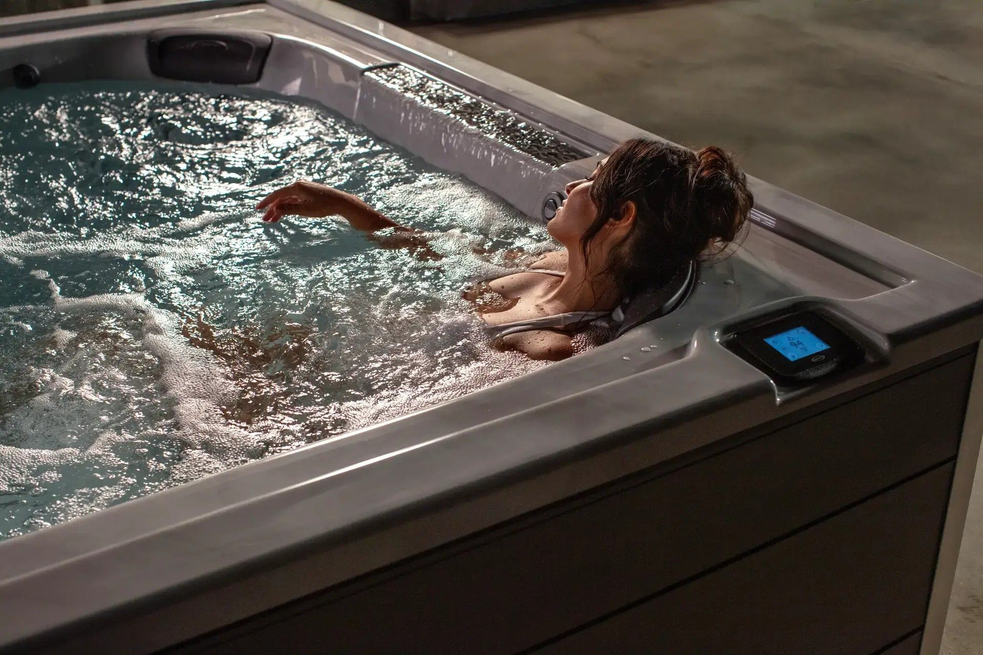 A woman is laying in a hot tub at night.