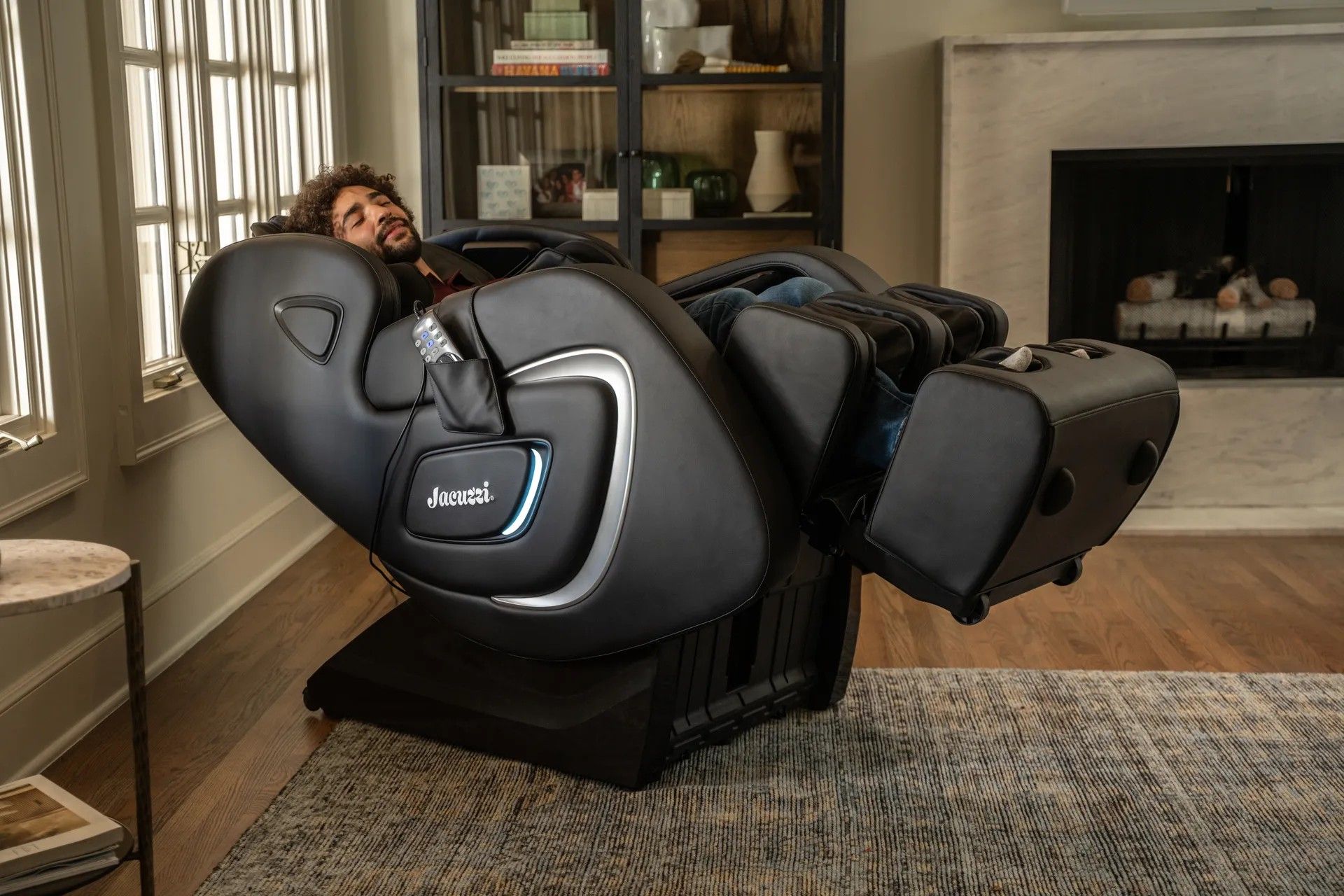 A man is sitting in a black massage chair in a living room.