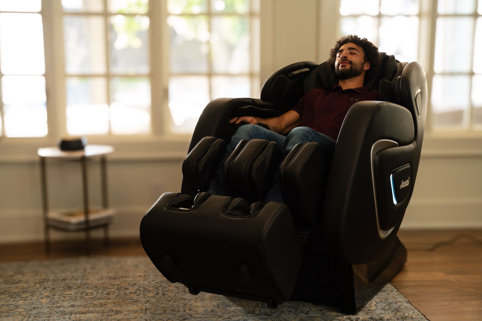 A man is sitting in a black massage chair in a living room.
