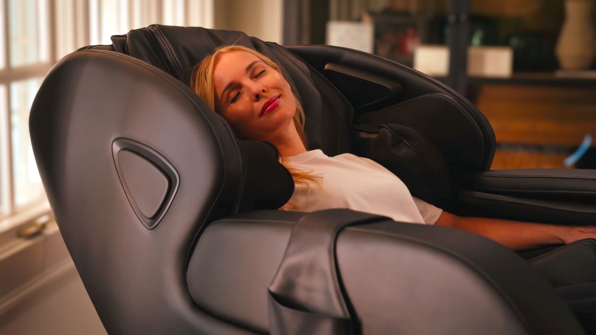 A woman is laying in a massage chair with her eyes closed.