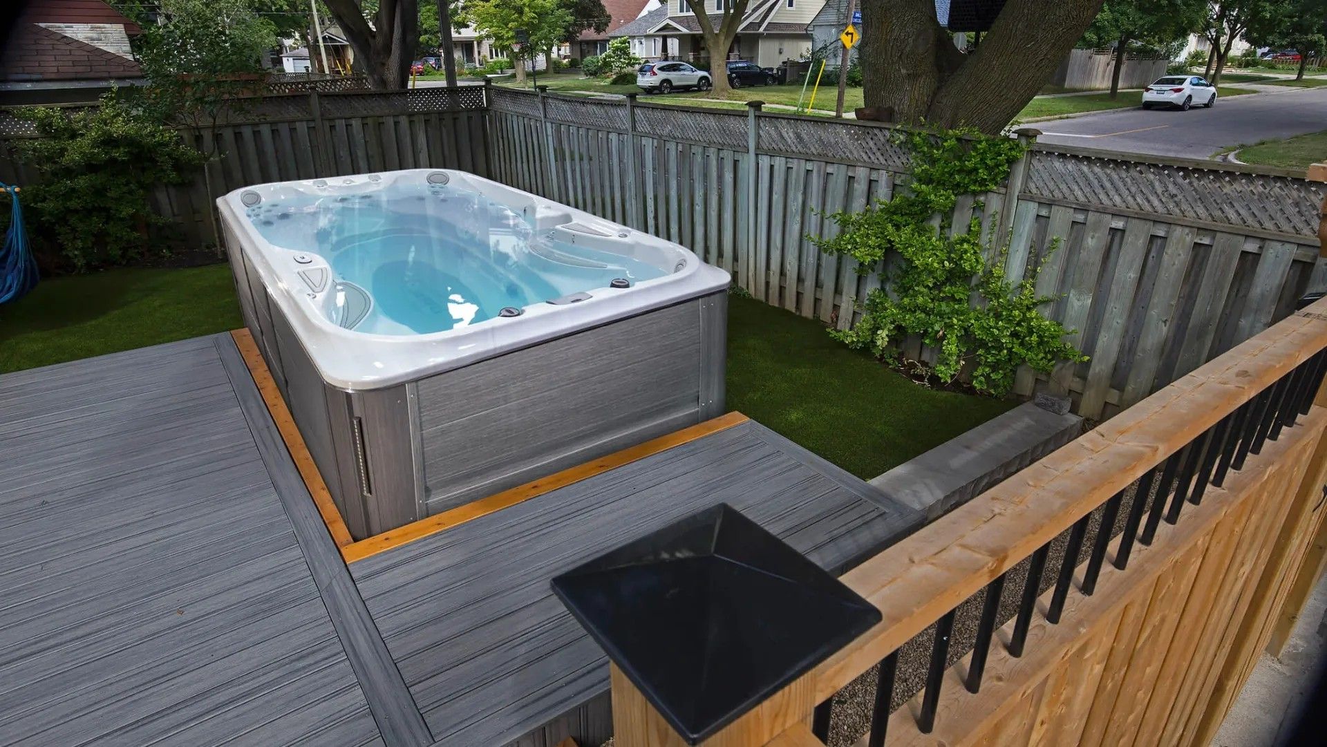 A hot tub is sitting on top of a wooden deck in a backyard.