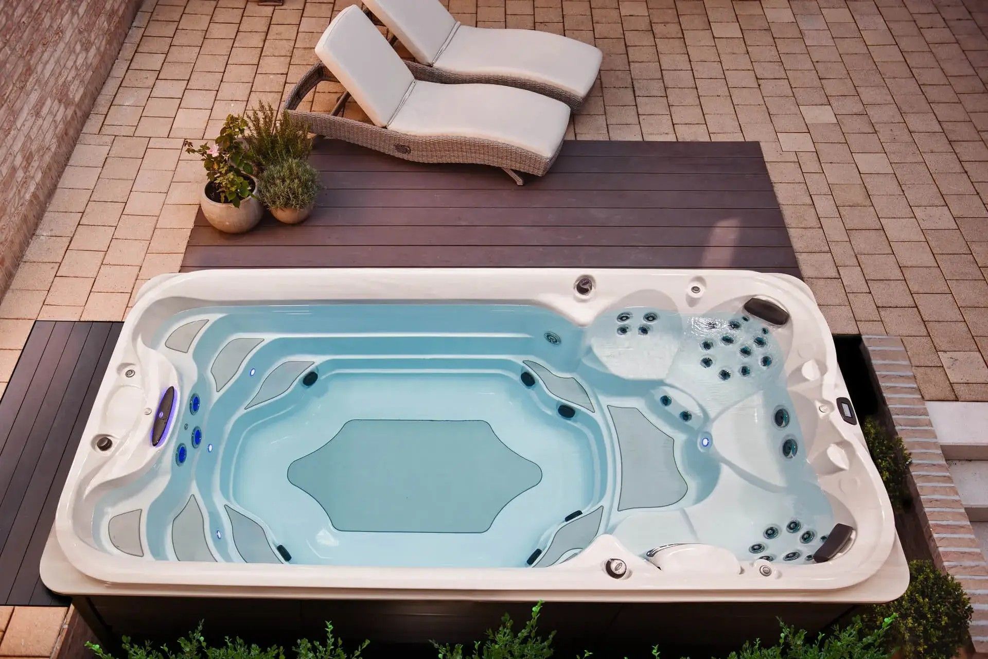 A large swimming pool is sitting on a patio next to two lounge chairs.