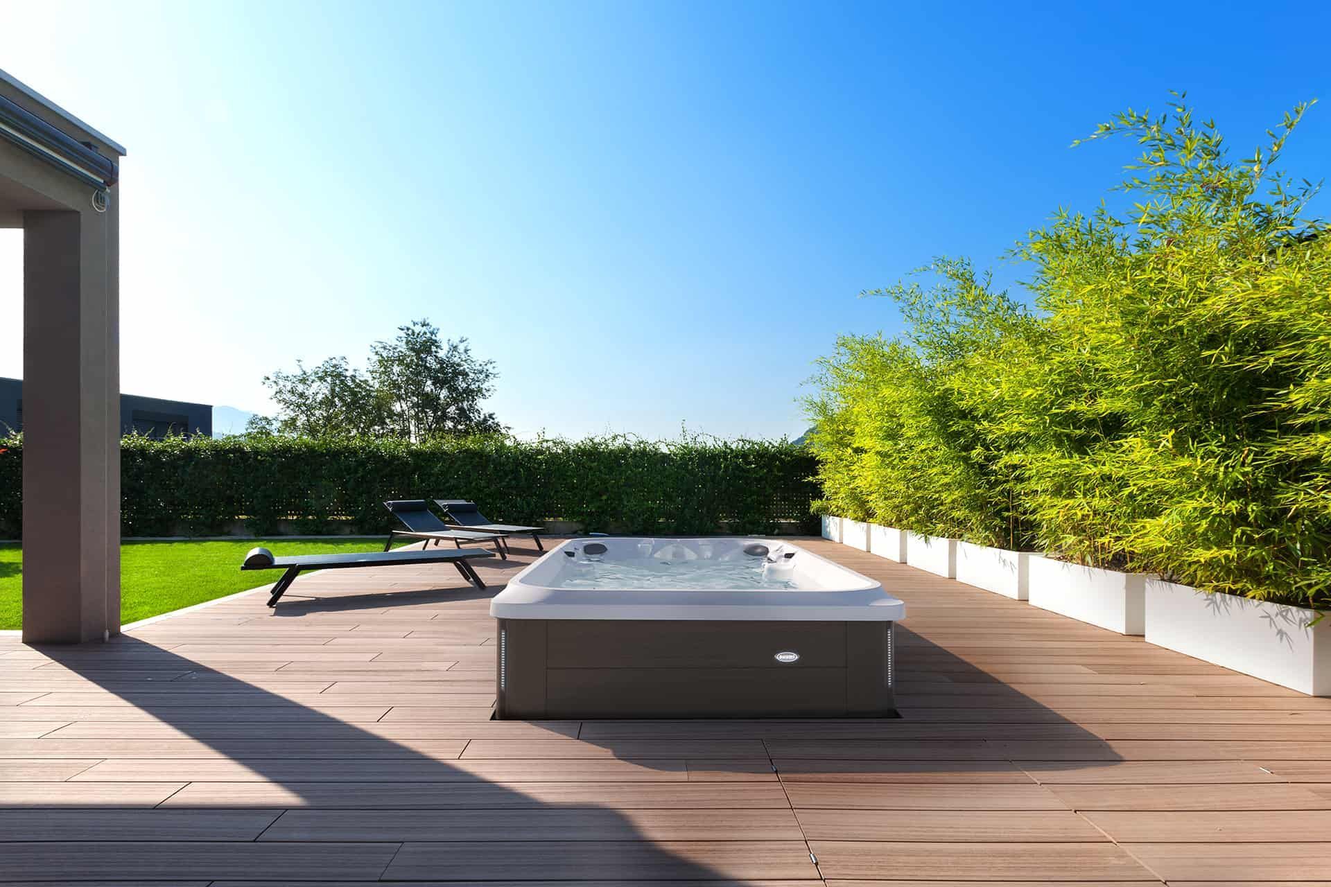 A hot tub is sitting on a wooden deck in the backyard of a house.