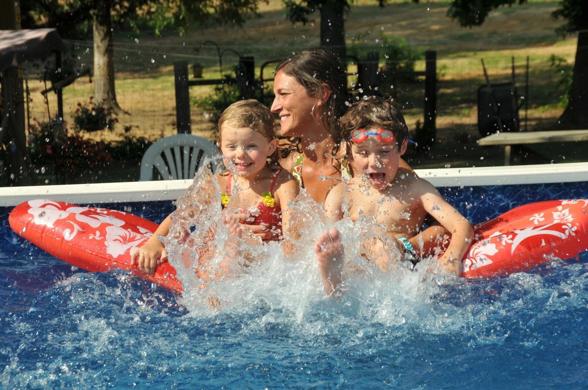 A woman and two children are playing in a swimming pool
