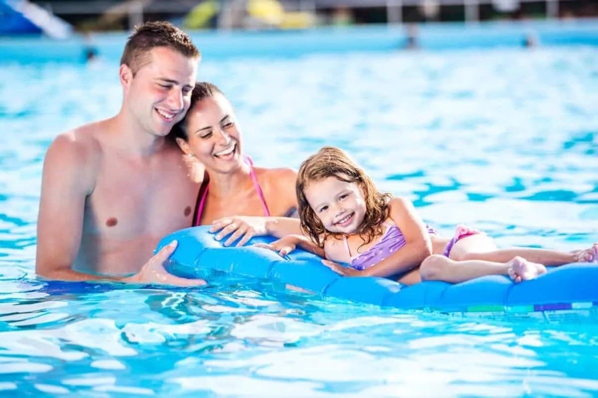 A man , woman and child are floating on a raft in a swimming pool.
