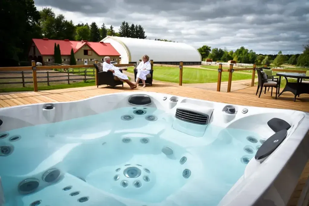 Two people are sitting in a hot tub on a deck.