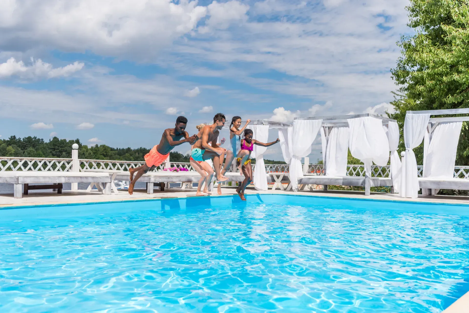 A group of people are jumping into a swimming pool.