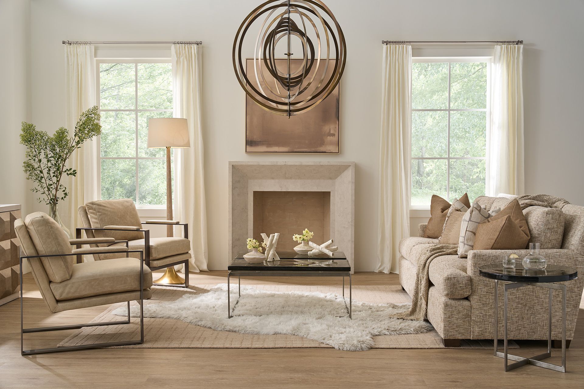 Bright living room with beige sofas, glass coffee table, fireplace, woven chandelier, and large windows