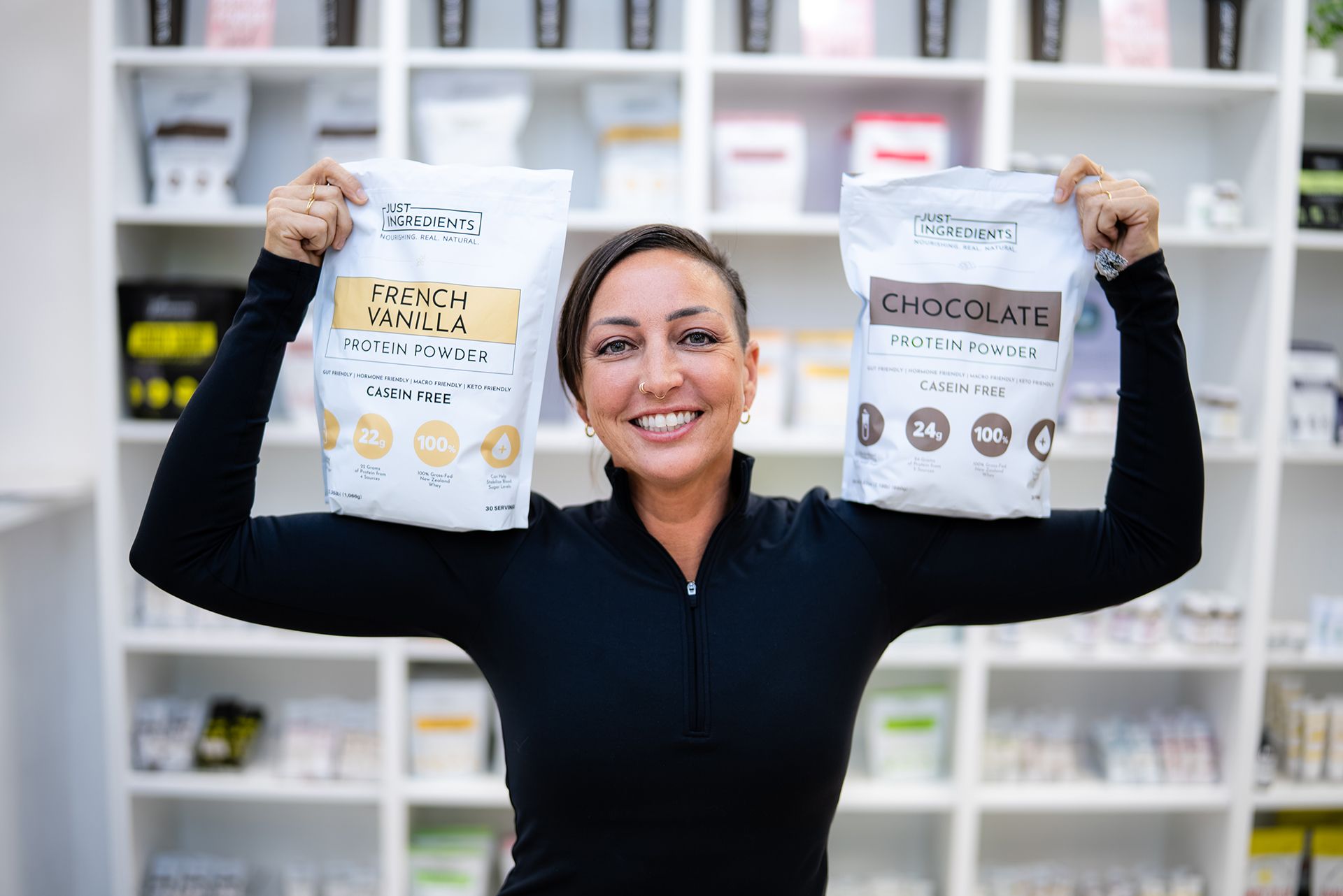 Woman smiling, holding bags of protein powder