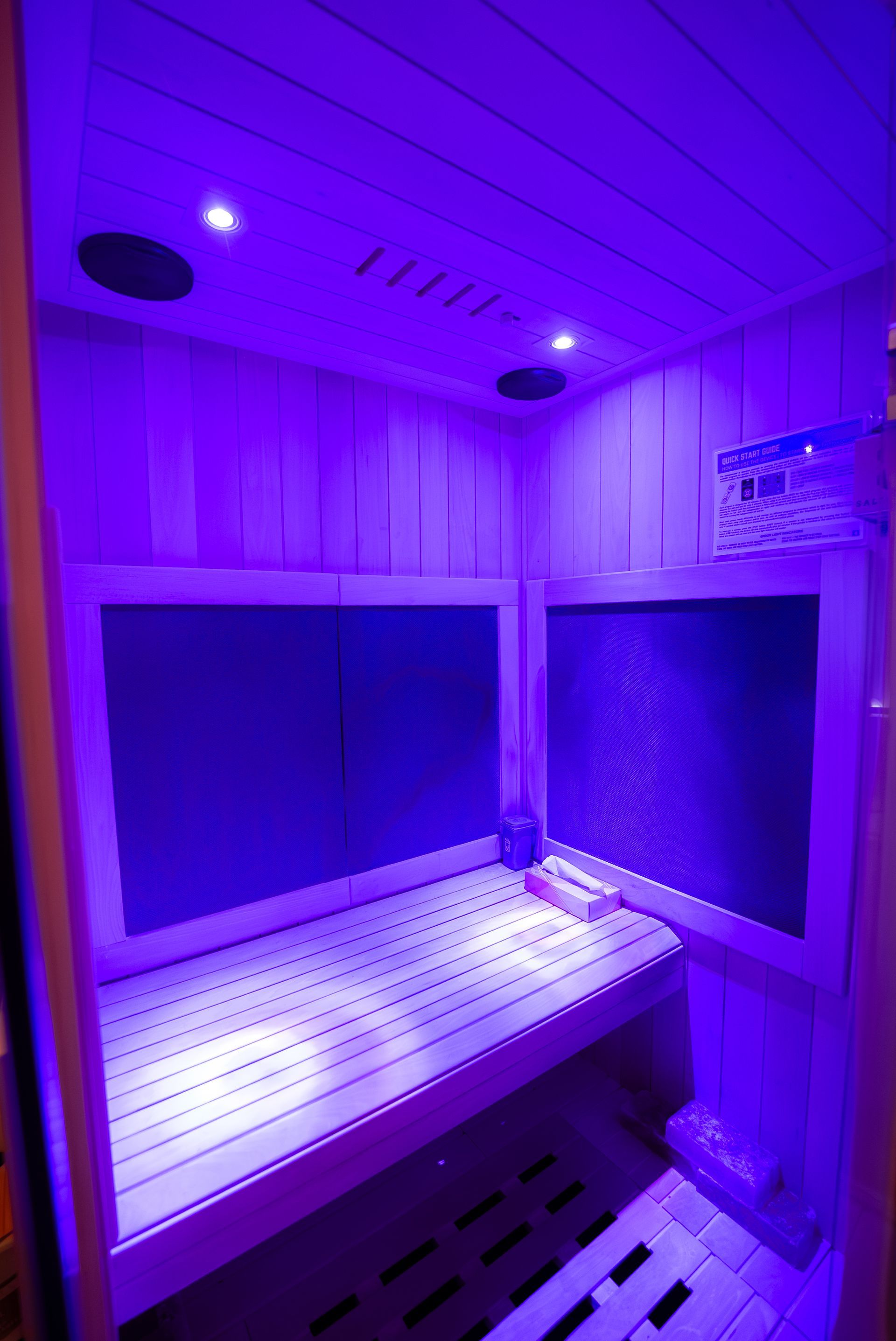 Interior of a sauna with wooden benches, walls, and purple lighting