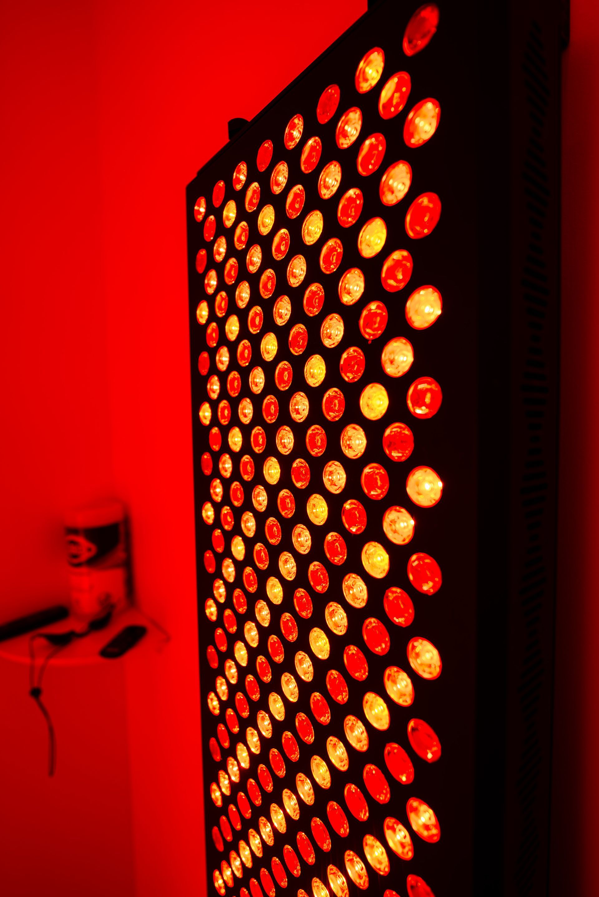 Red light therapy panel, mounted on a wall, emitting a warm red glow