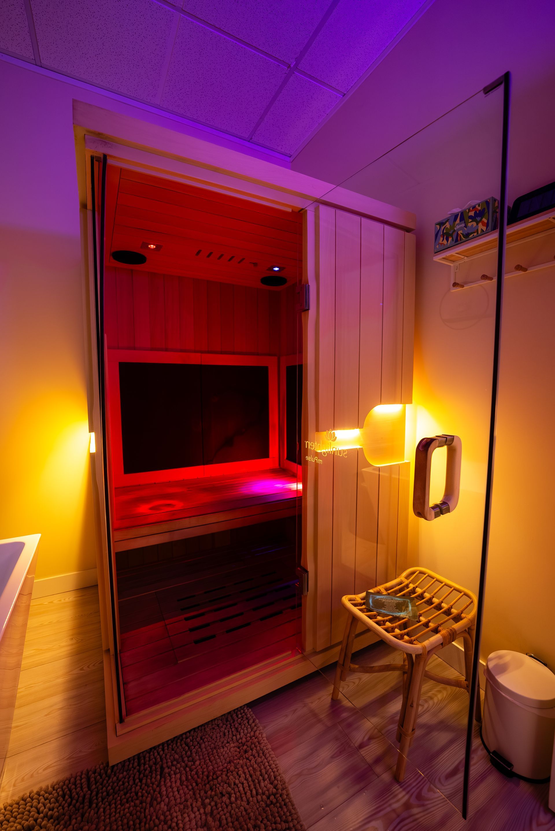 Infrared sauna with open door, illuminated in red