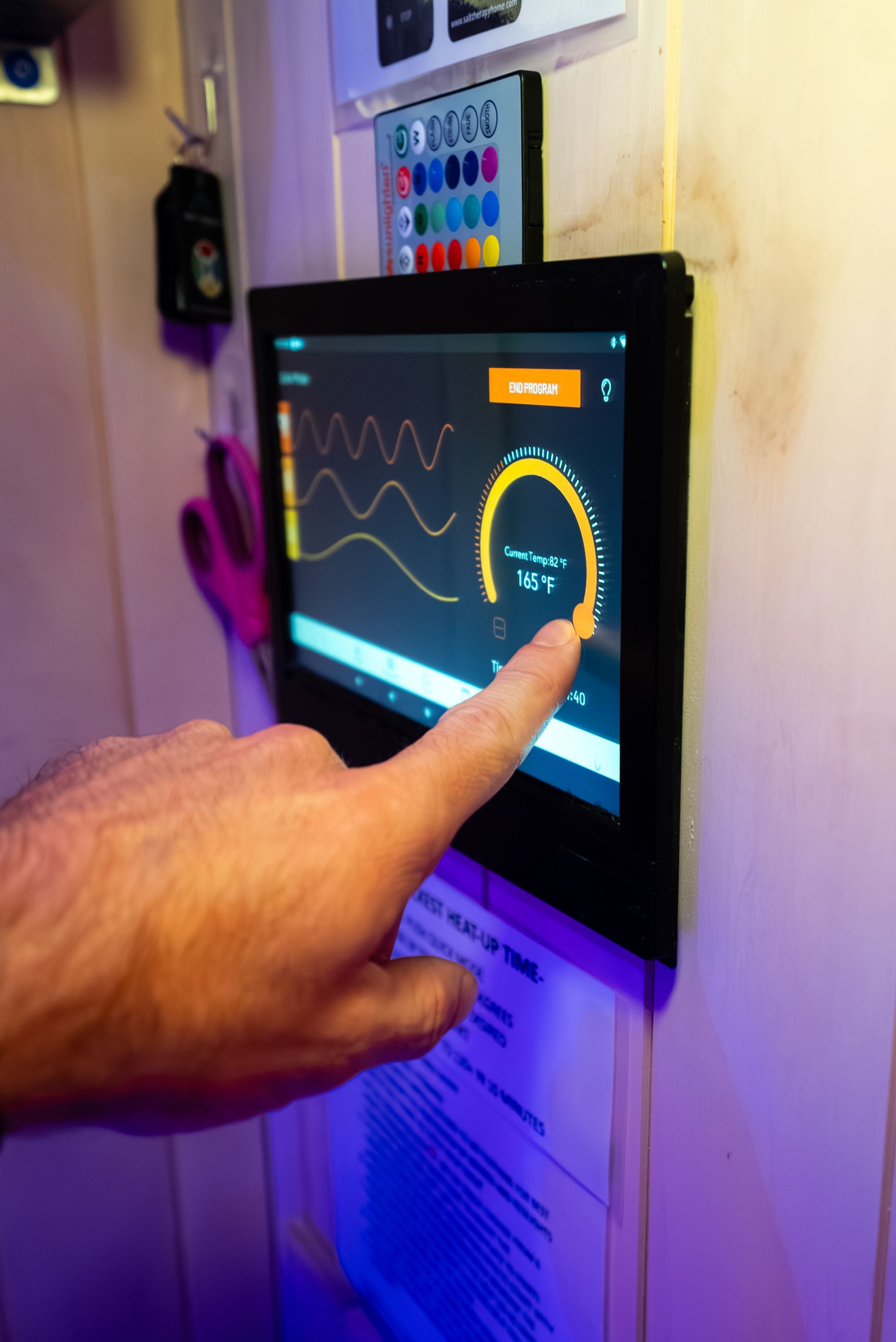 A person's hand touching a digital display showing graphs and data on a wall
