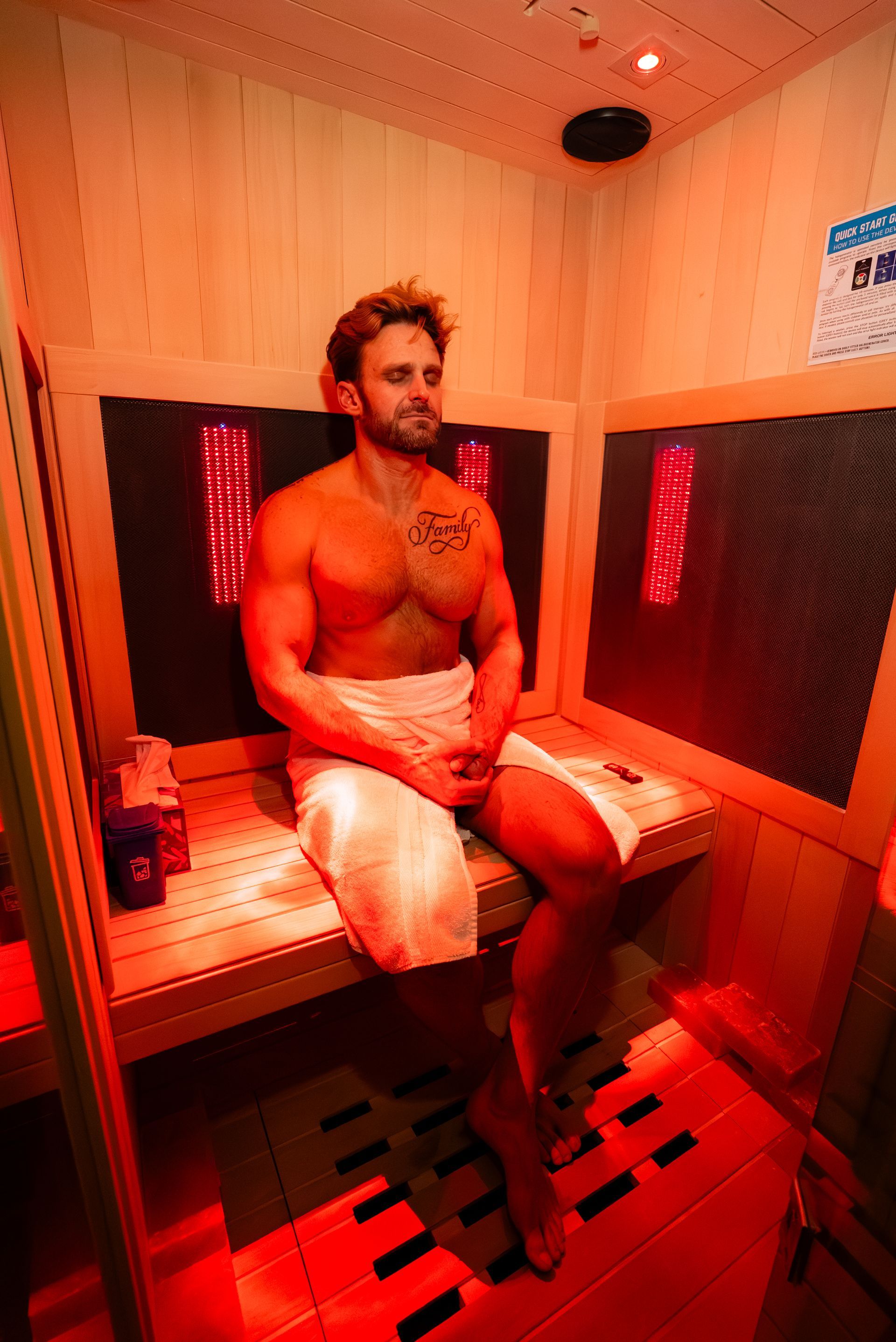 Man sitting in a red-lit infrared sauna