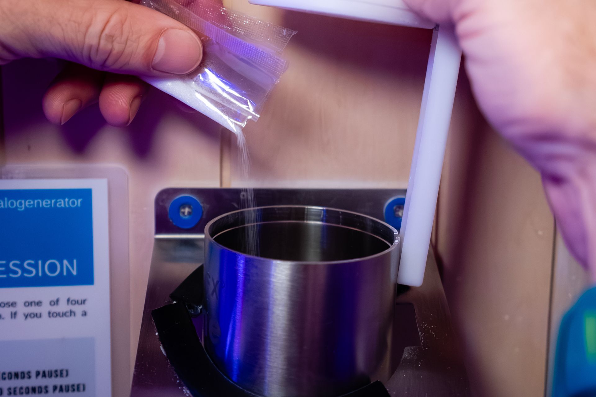 Person pouring salt from a clear pouch into a metal container