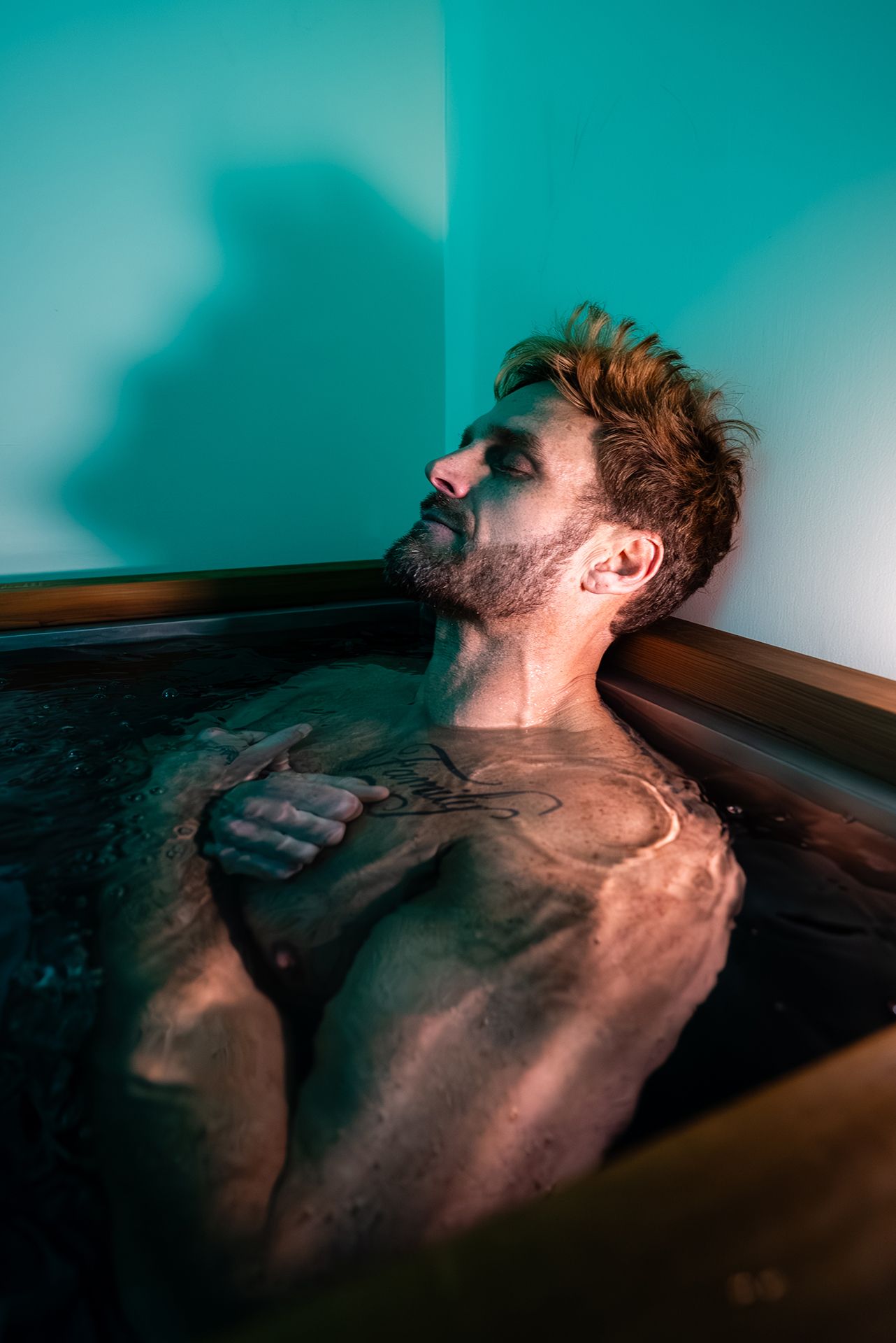 Man relaxing in a cold plunge tub with arms crossed over chest