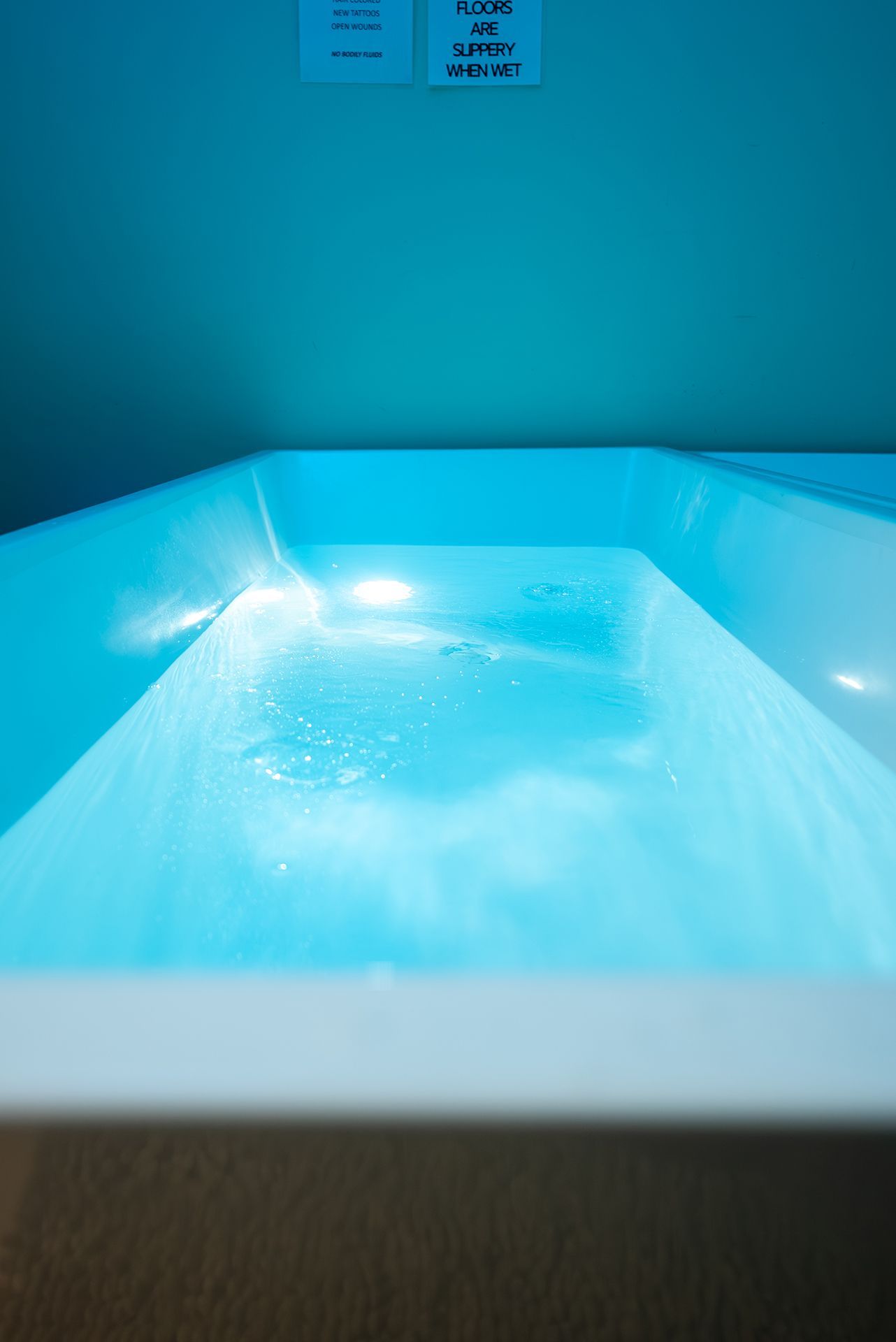 Blue-lit tubs filled with water, in a light blue room