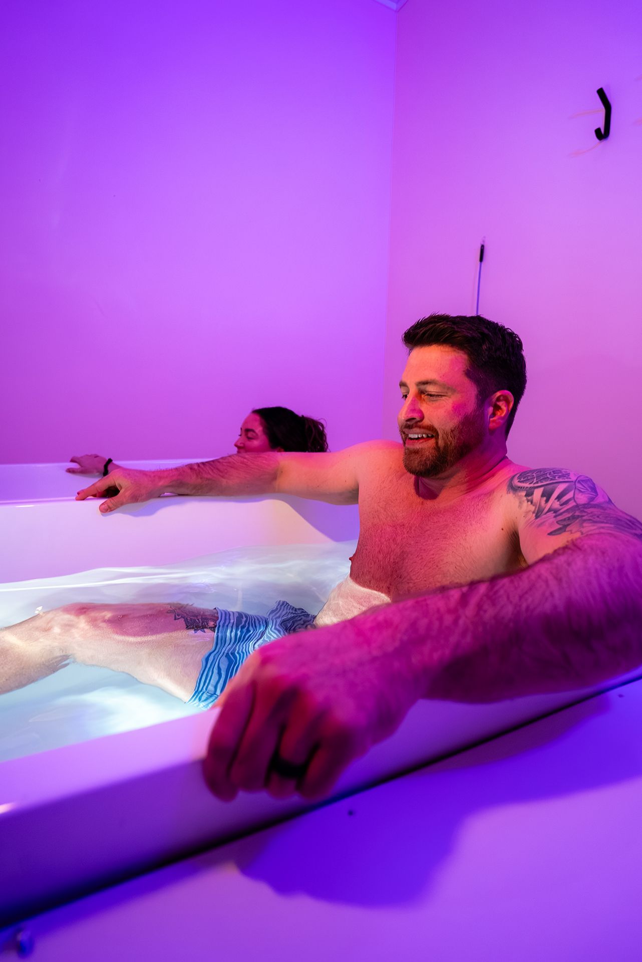 Man and woman relaxing in a tub with purple lighting
