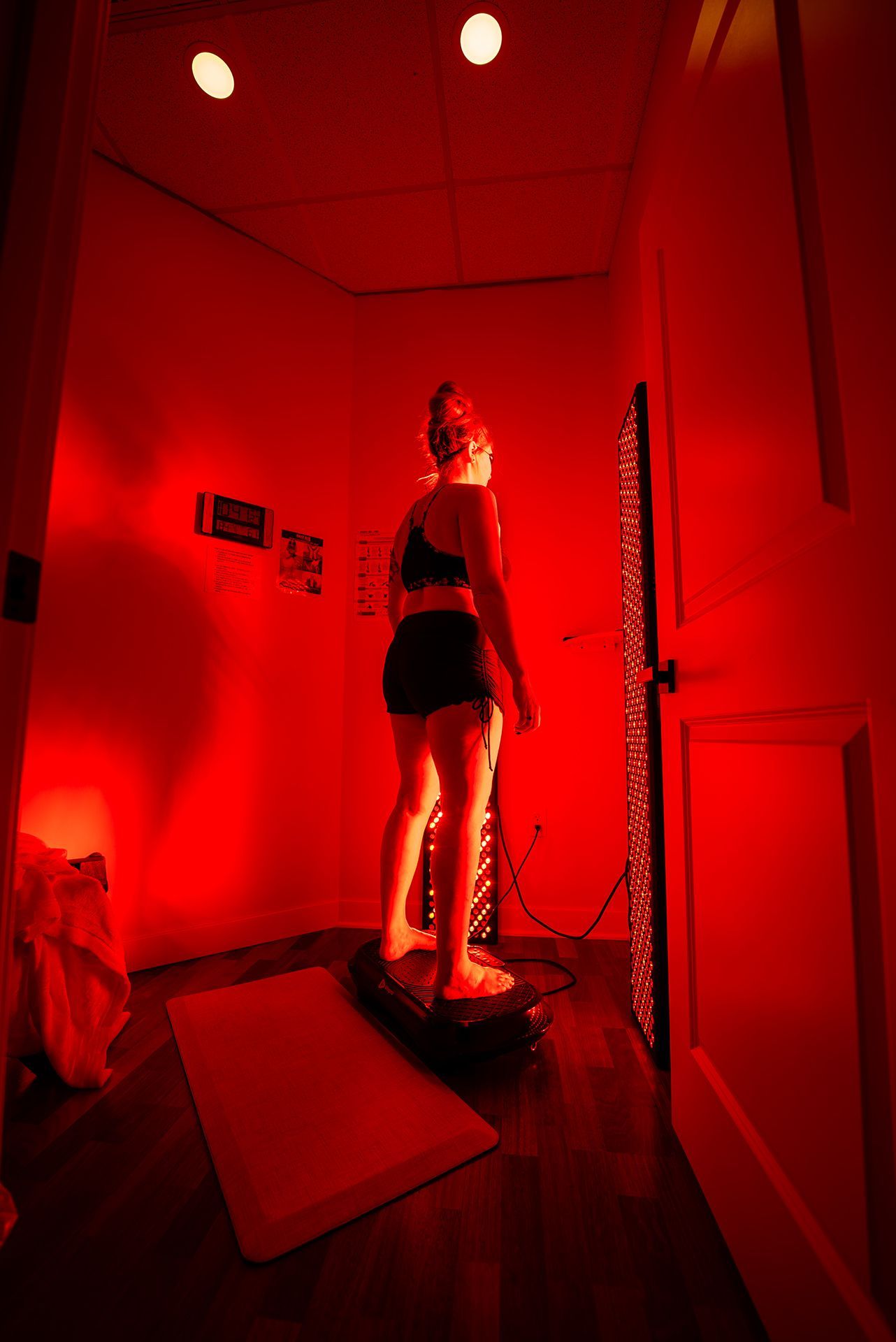 Woman in black workout clothes stands in red-lit room