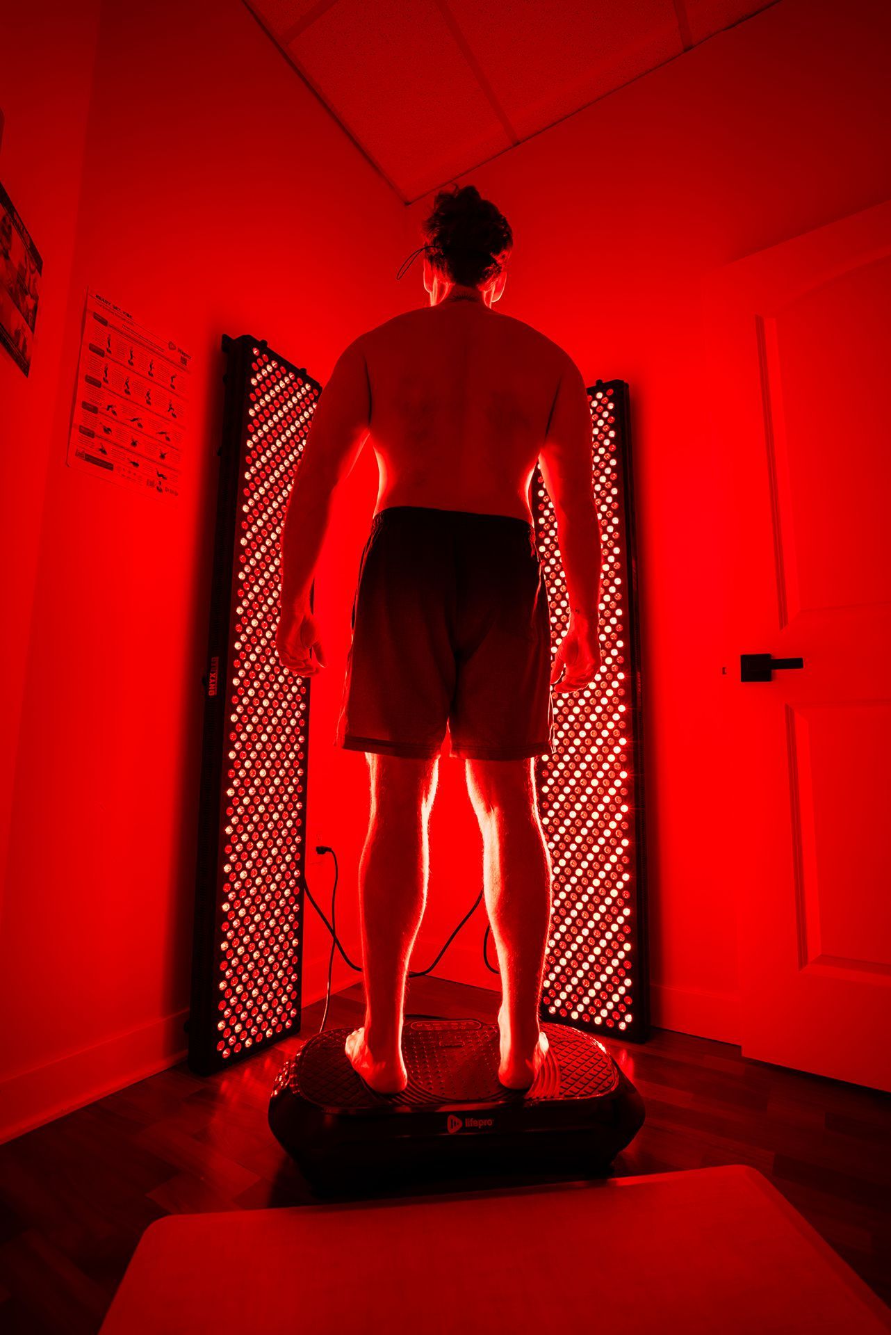 Man standing on platform, facing red light panels