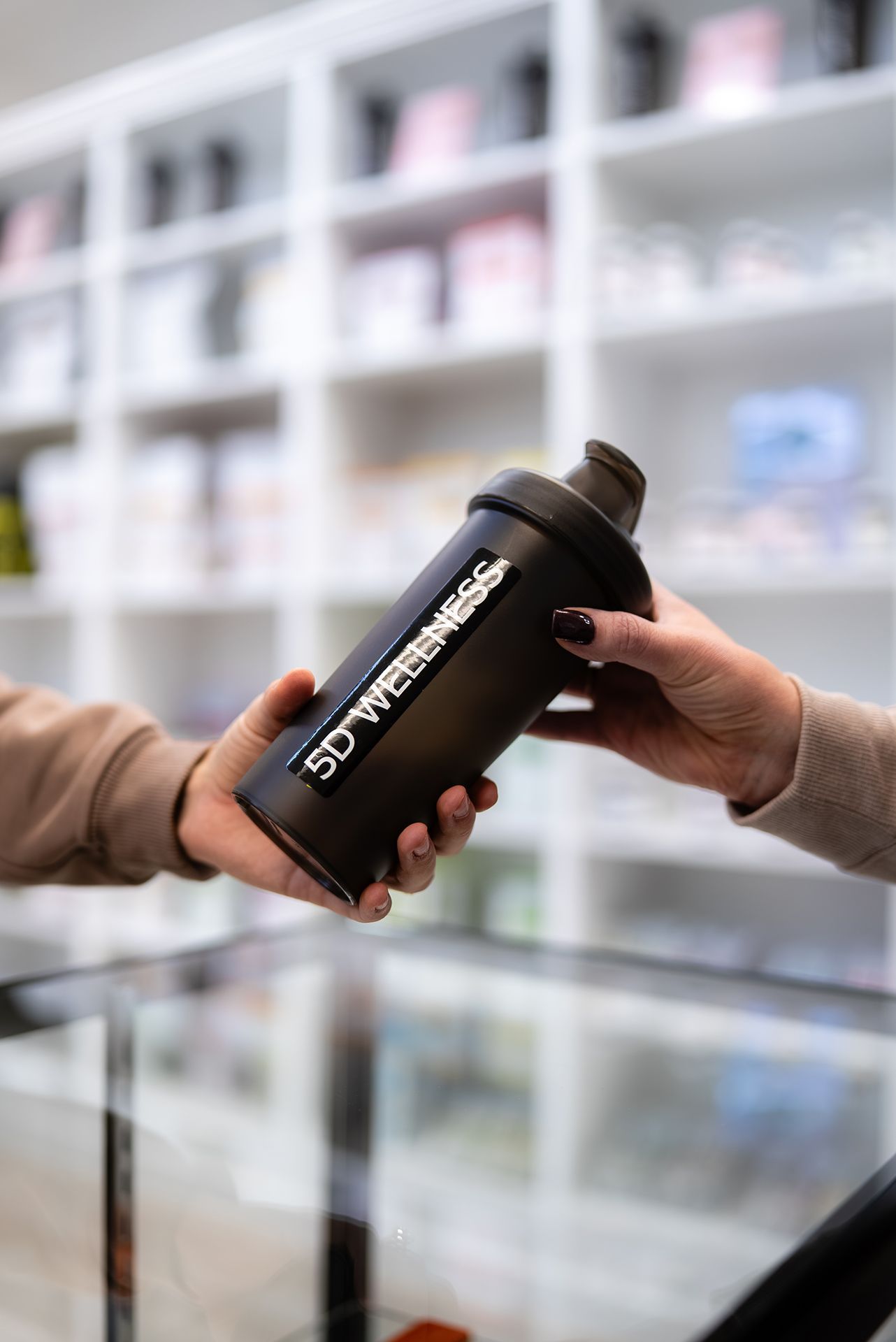 Two hands exchanging a black protein shaker