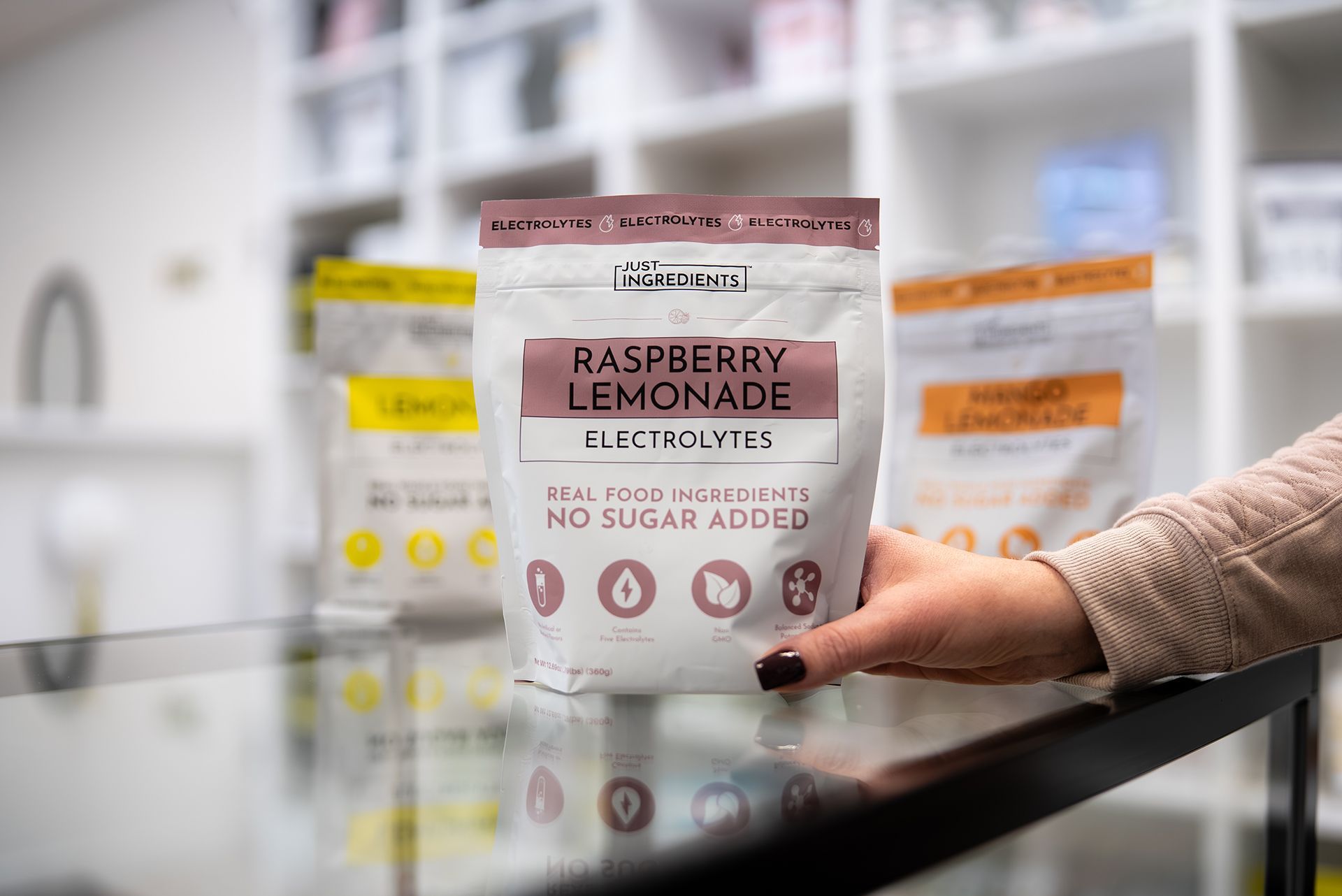 Hand holding a Raspberry Lemonade Electrolyte powder bag