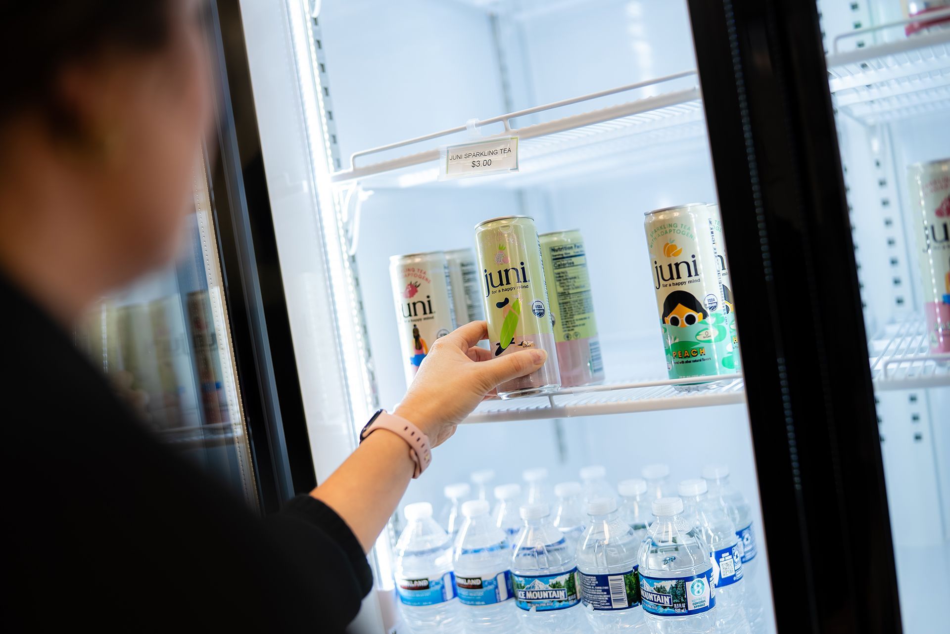 Person reaching into a refrigerator for a can of beverage