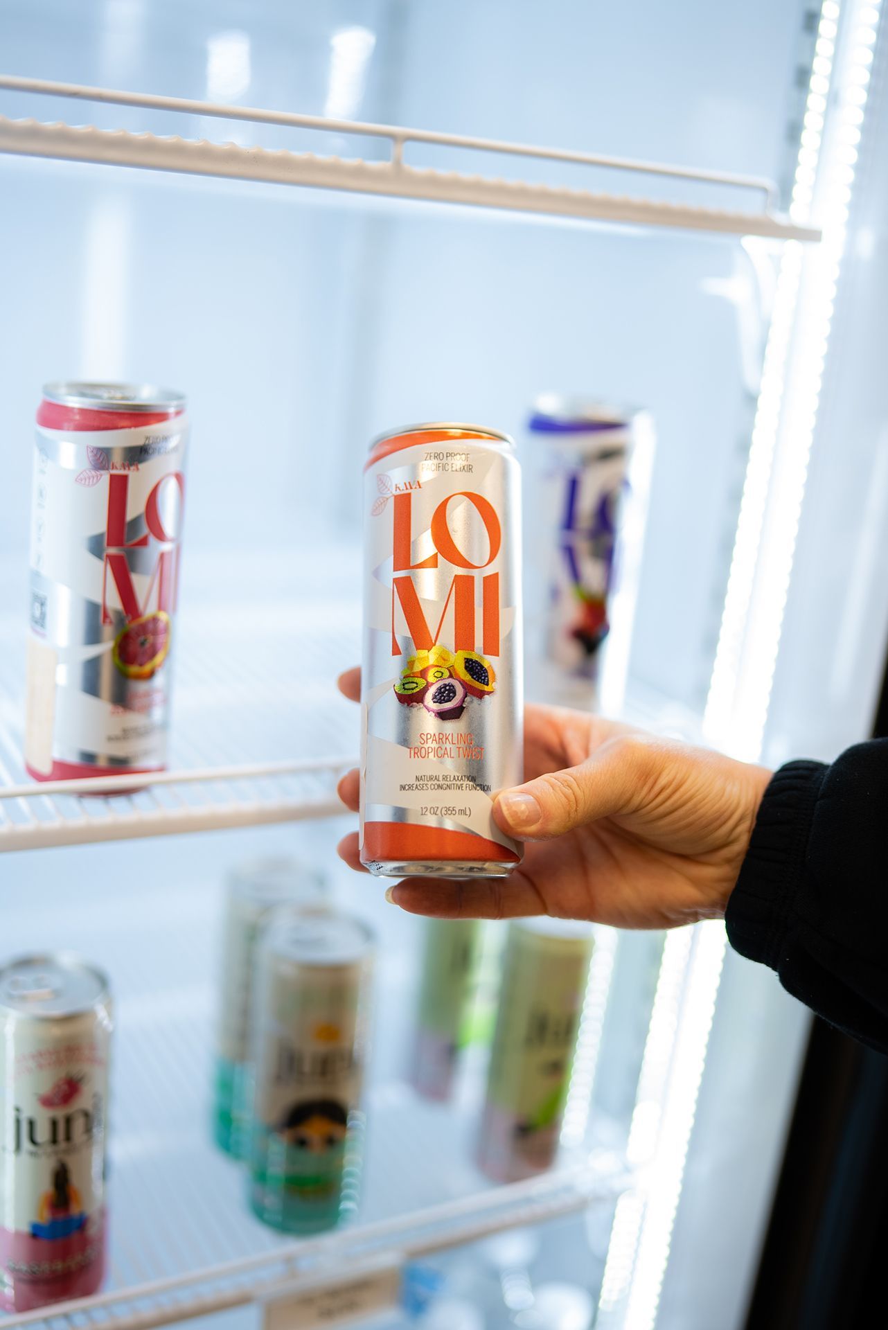 Hand holding a beverage can from a refrigerated display