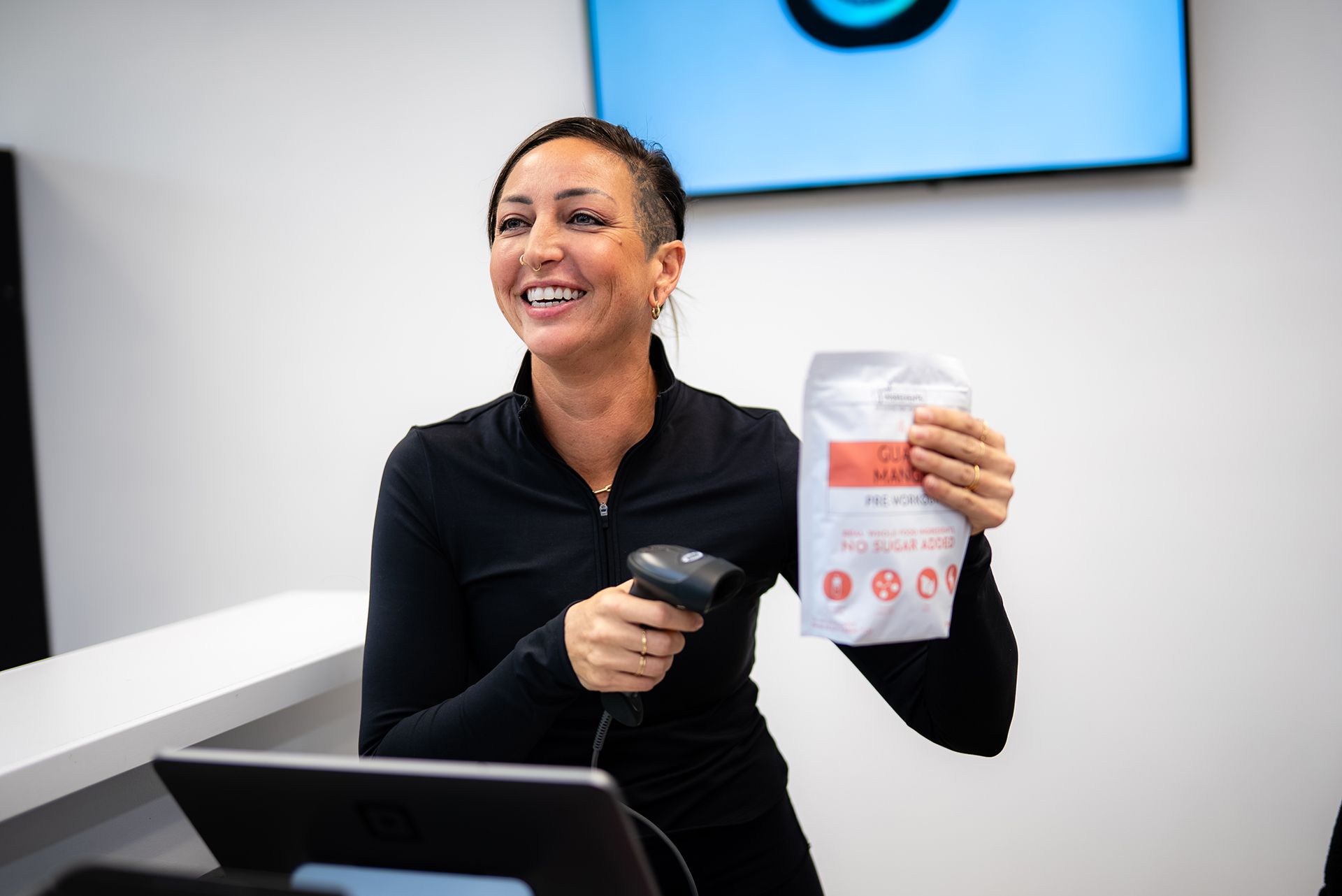 Woman holding product bag, scanning barcode, and smiling