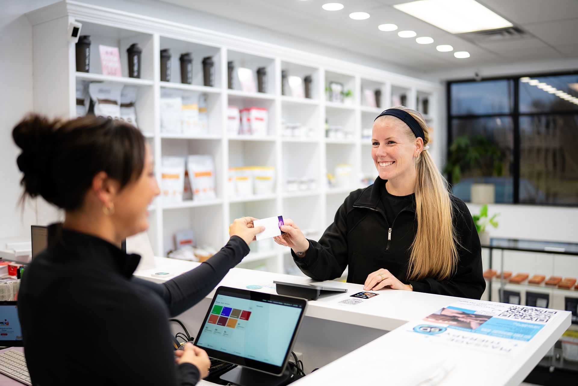 Woman hands card to employee at counter in health store