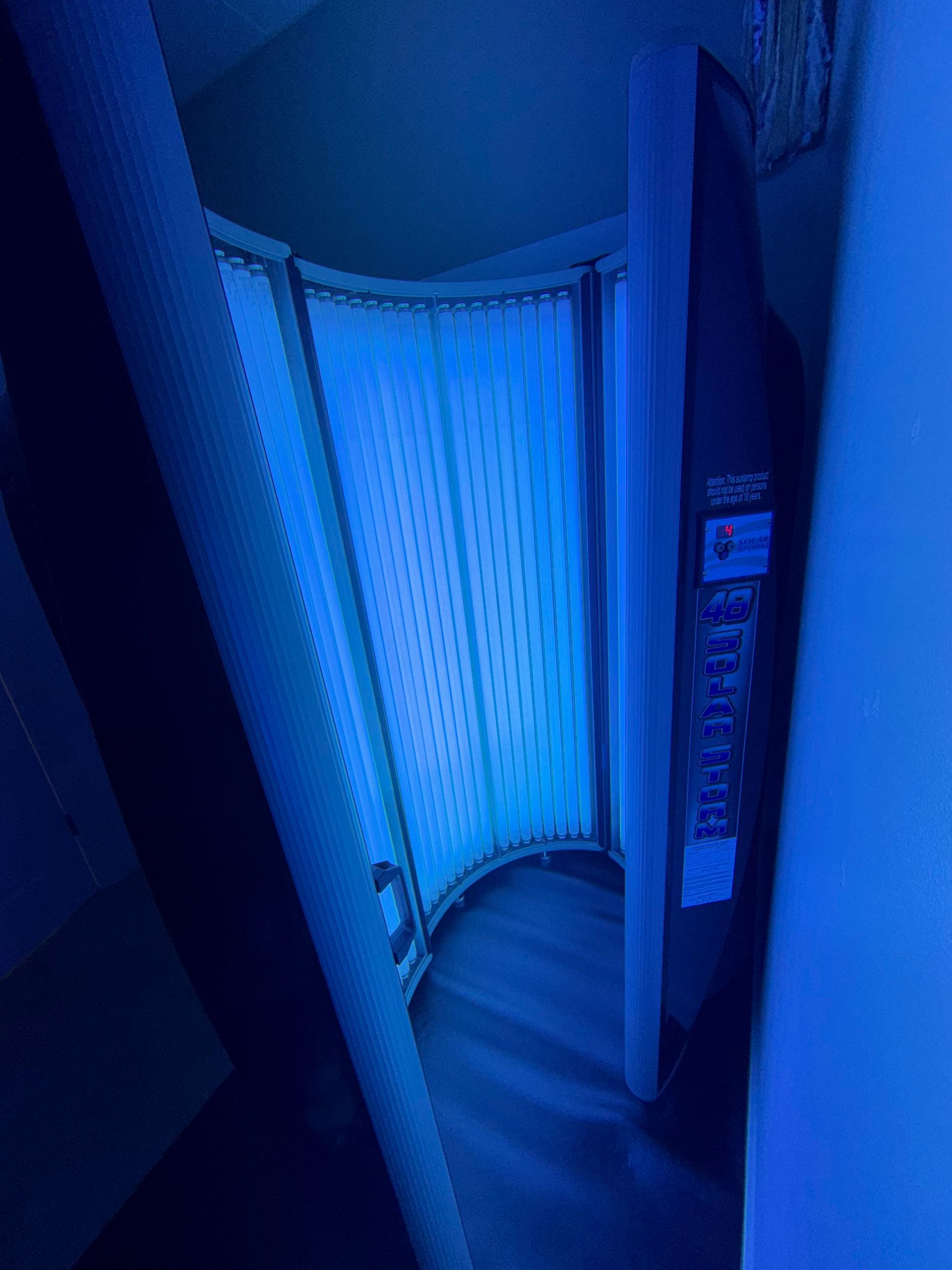 Blue-lit curved shower stall with a closed curtain and tiled walls