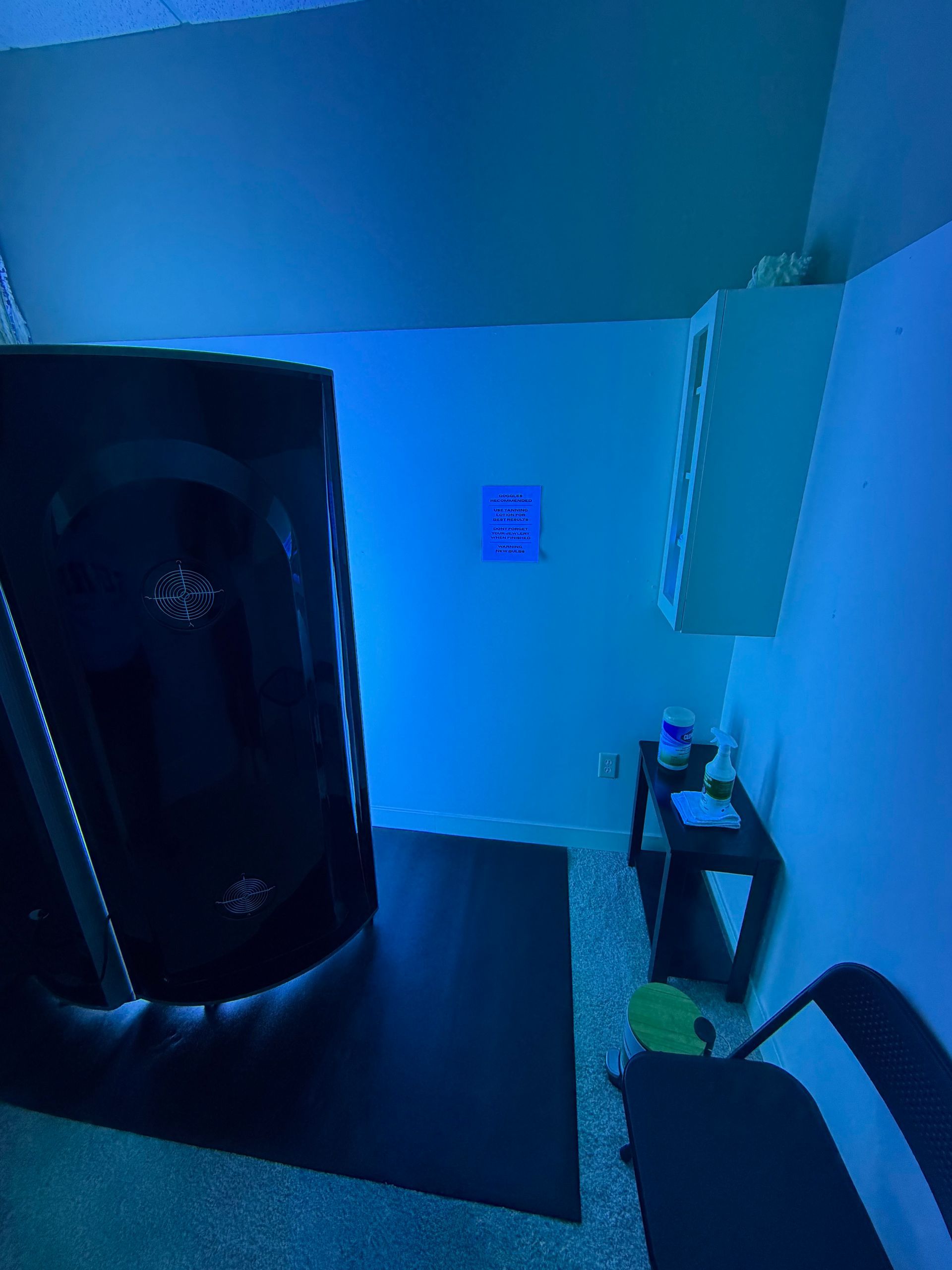 Blue-lit bathroom with a shower, toilet, and small sink area