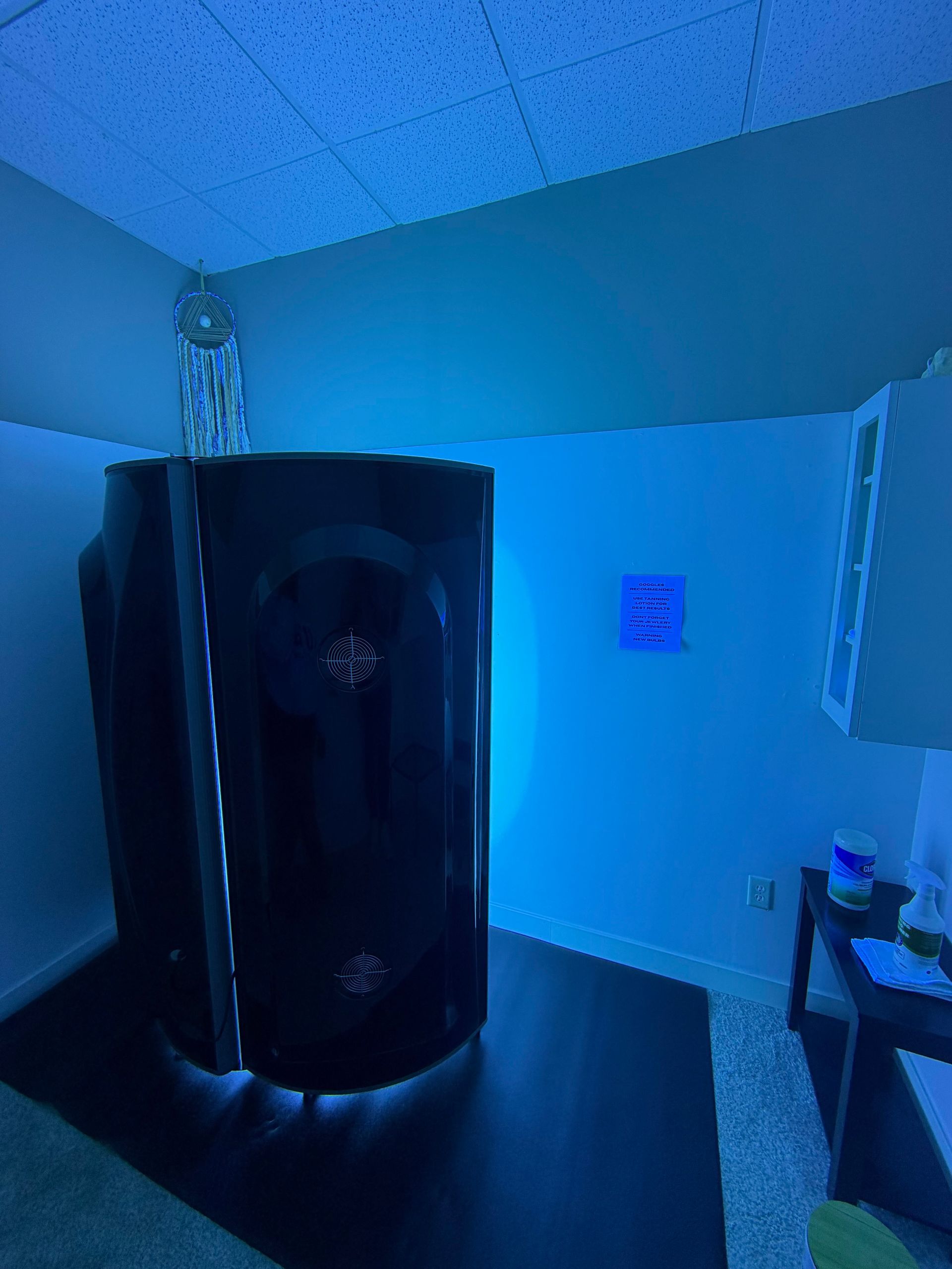 Blue-lit bathroom with a black shower stall, white walls, and a sink counter on the right.