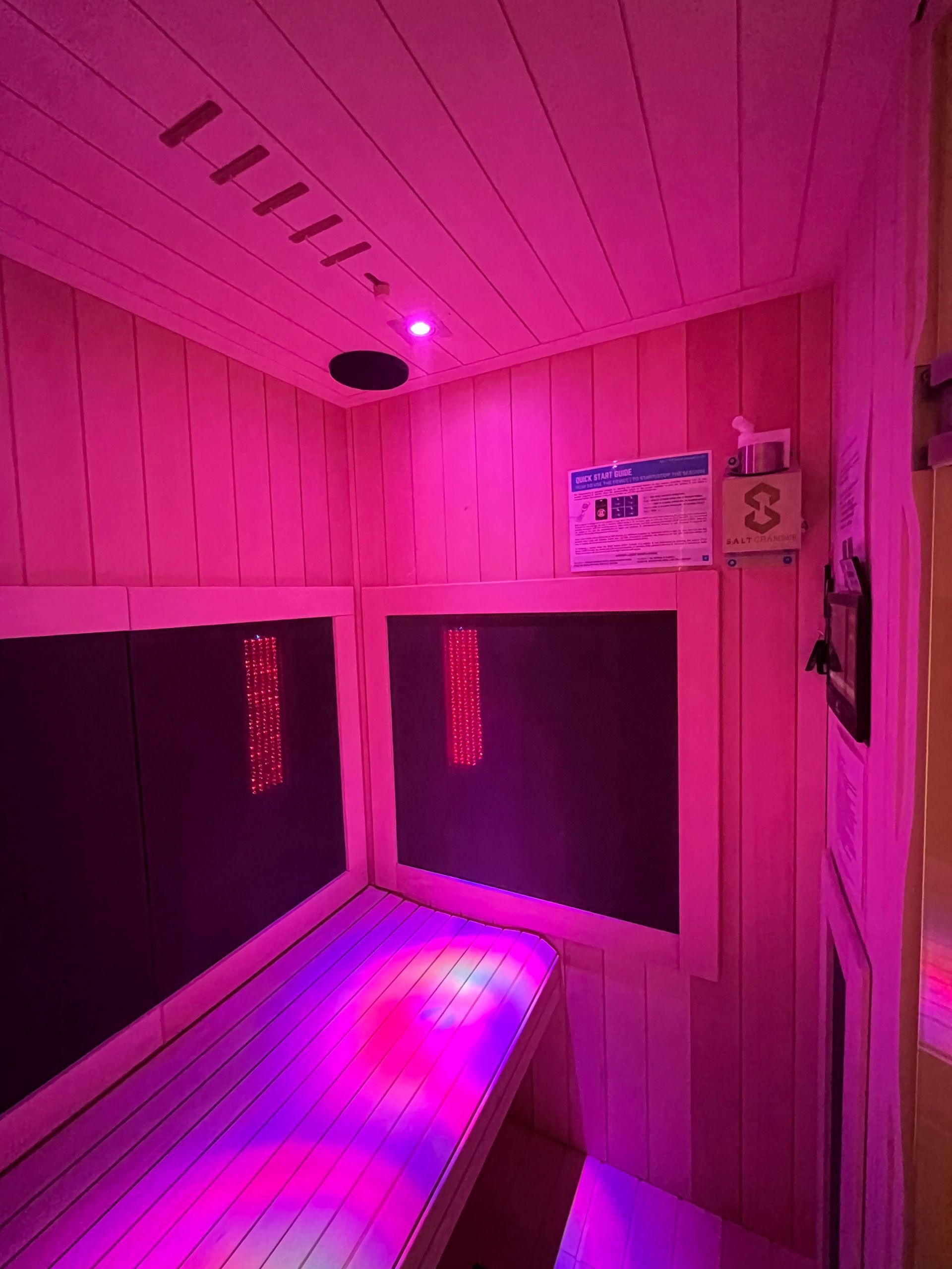 a pink sauna with purple lights on the walls and ceiling .