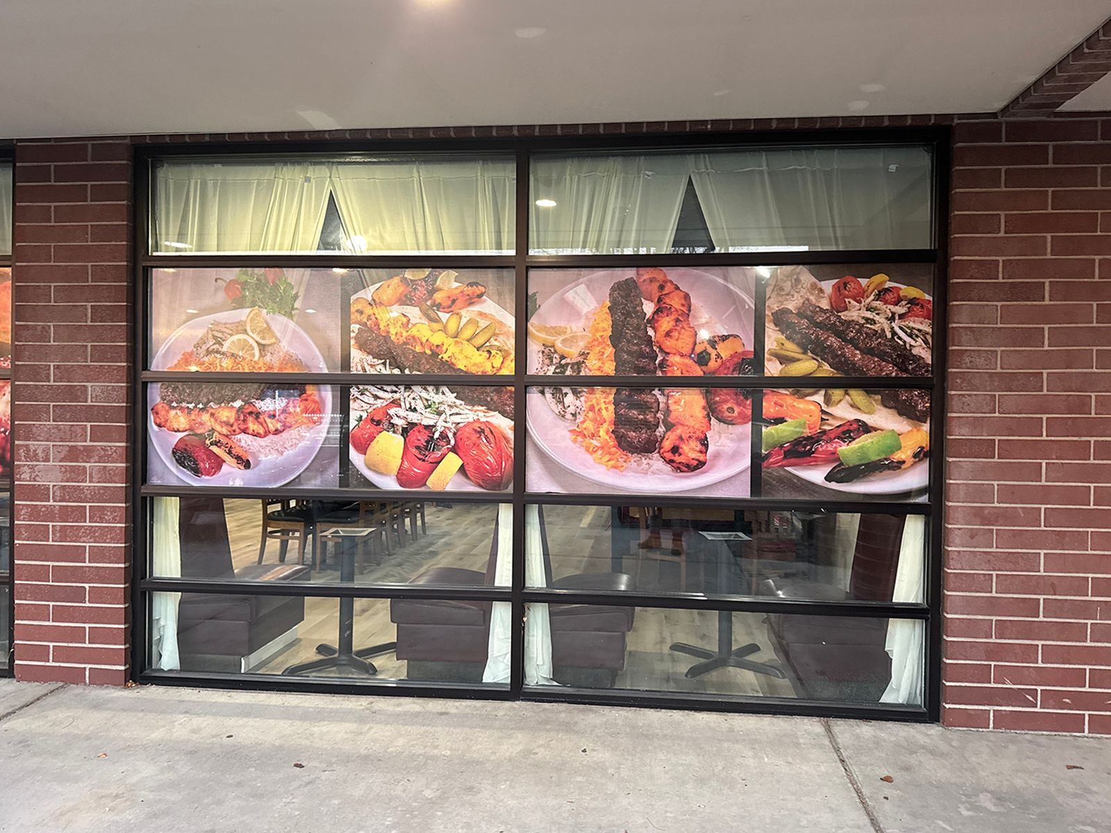 Restaurant storefront with window displays of food and interior reflection.
