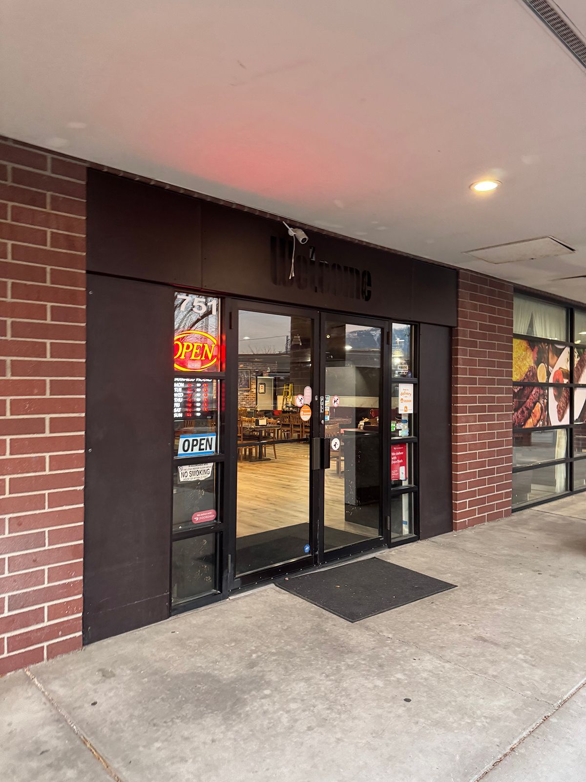 Black storefront with glass doors; red brick on sides, concrete walkway.