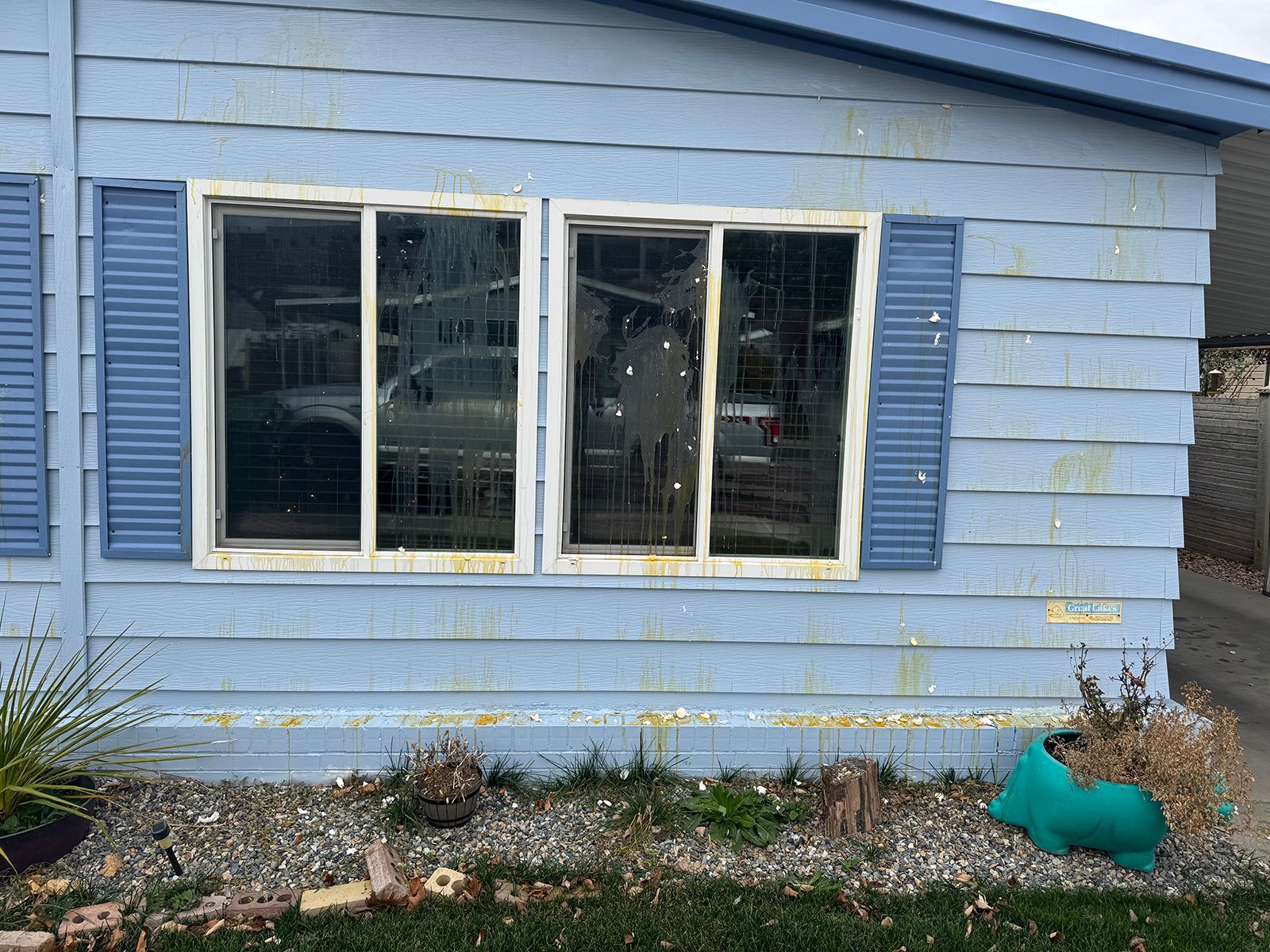Blue house with two windows, blue shutters, and weathered siding.
