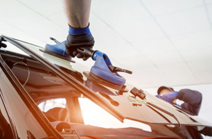 A man is installing a windshield on a car.