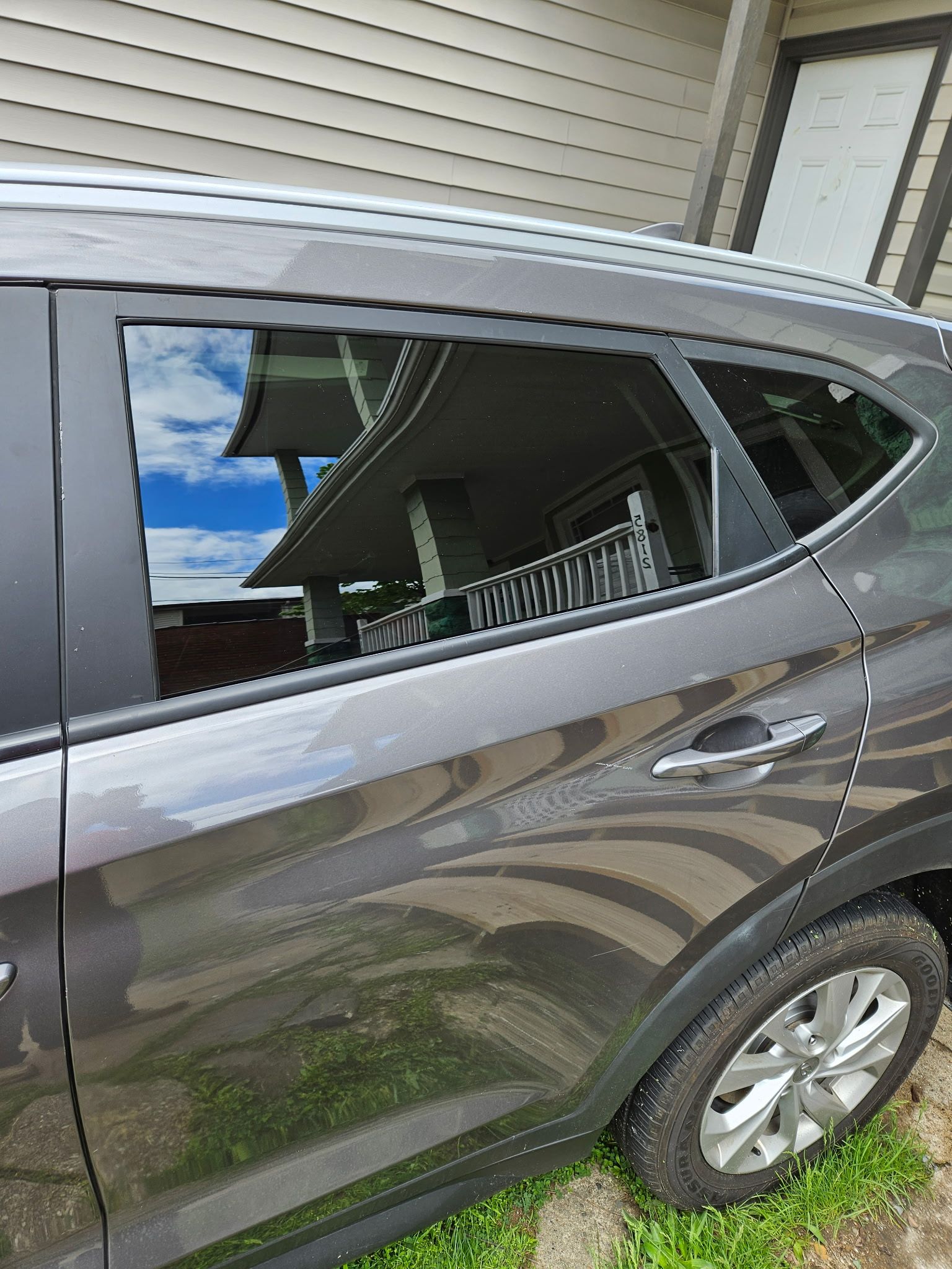 A gray car is parked in front of a house.
