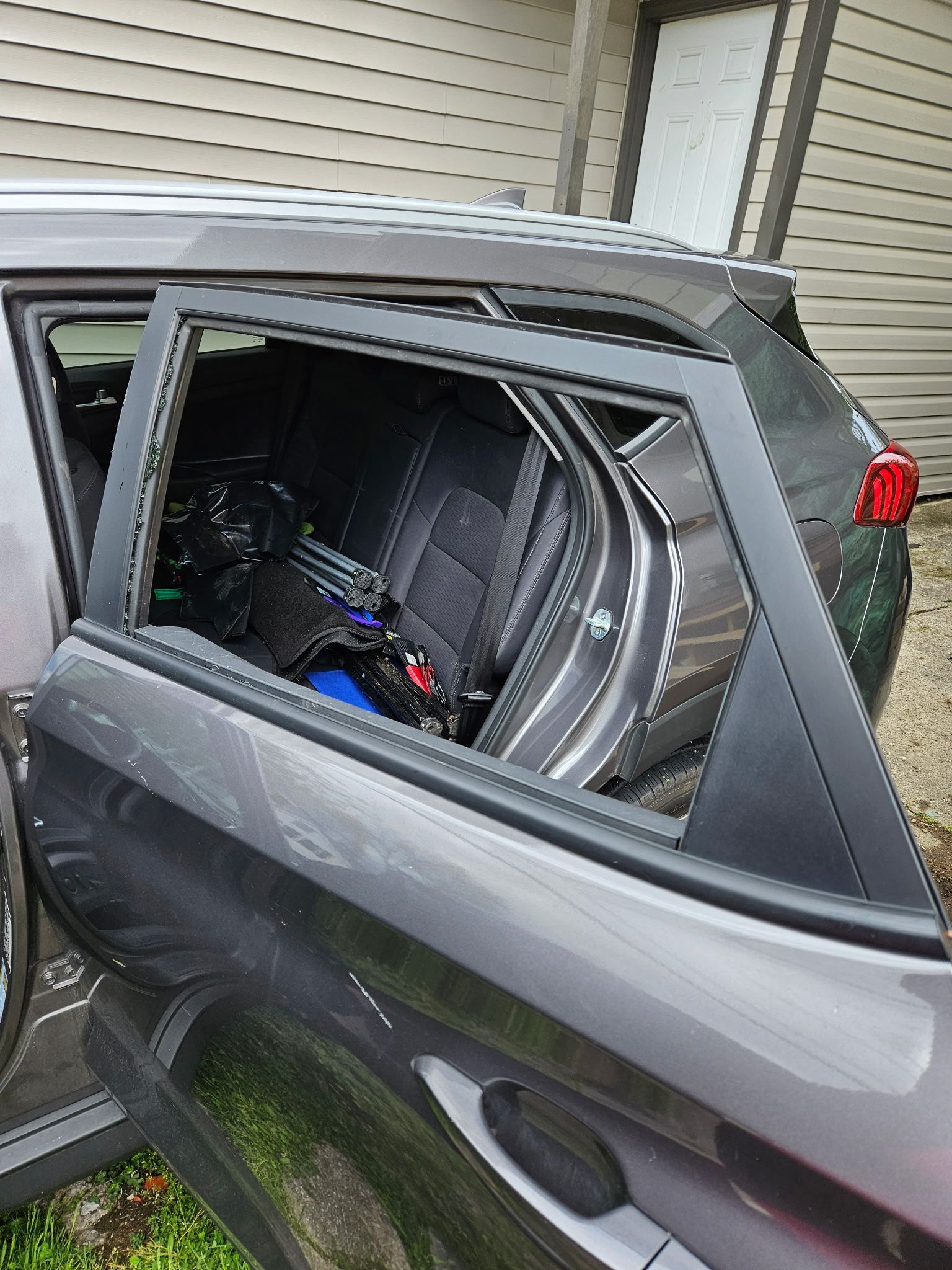 A car with a broken window is parked in front of a garage.